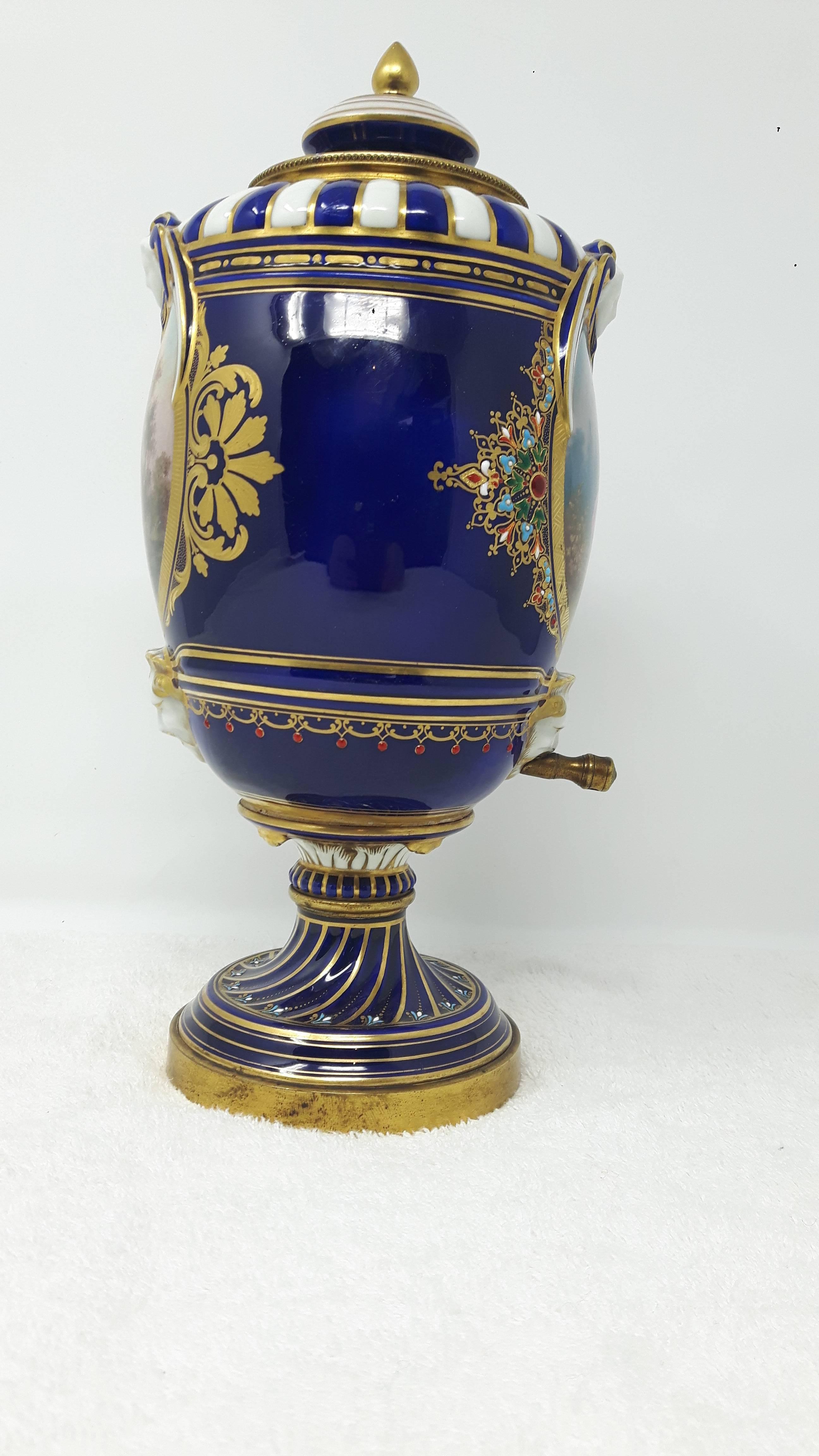 A beautiful and very unusual jewelled porcelain samovar, Sèvres porcelain from the 18 century but decorated in the first quarter of the 19th century, probably in the workshop of Emil Lévy.
The body is hand painted in blue and decorated with rich