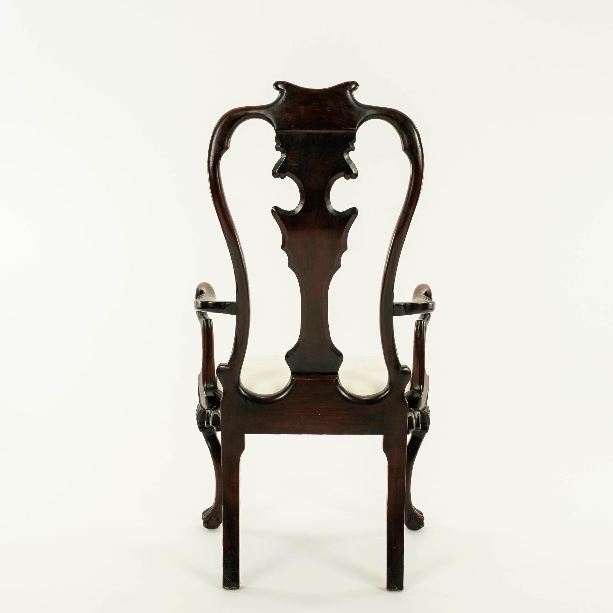 19th century Portuguese Rococo style mahogany arm chair featuring a scrolled crest on a double yolk back centering a shaped flat splat, scalloped seat rail centering a stylized splayed leaf pendant raised on exaggerated cabriole legs with foliate
