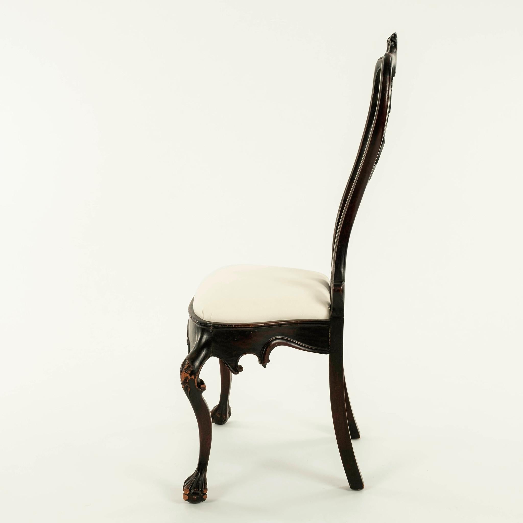 19th century Portuguese Rococo style mahogany chair featuring a scrolled crest on a double yolk back centering a shaped flat splat, scalloped seat rail centering a stylized splayed leaf pendant raised on exaggerated cabriole legs with foliate carved
