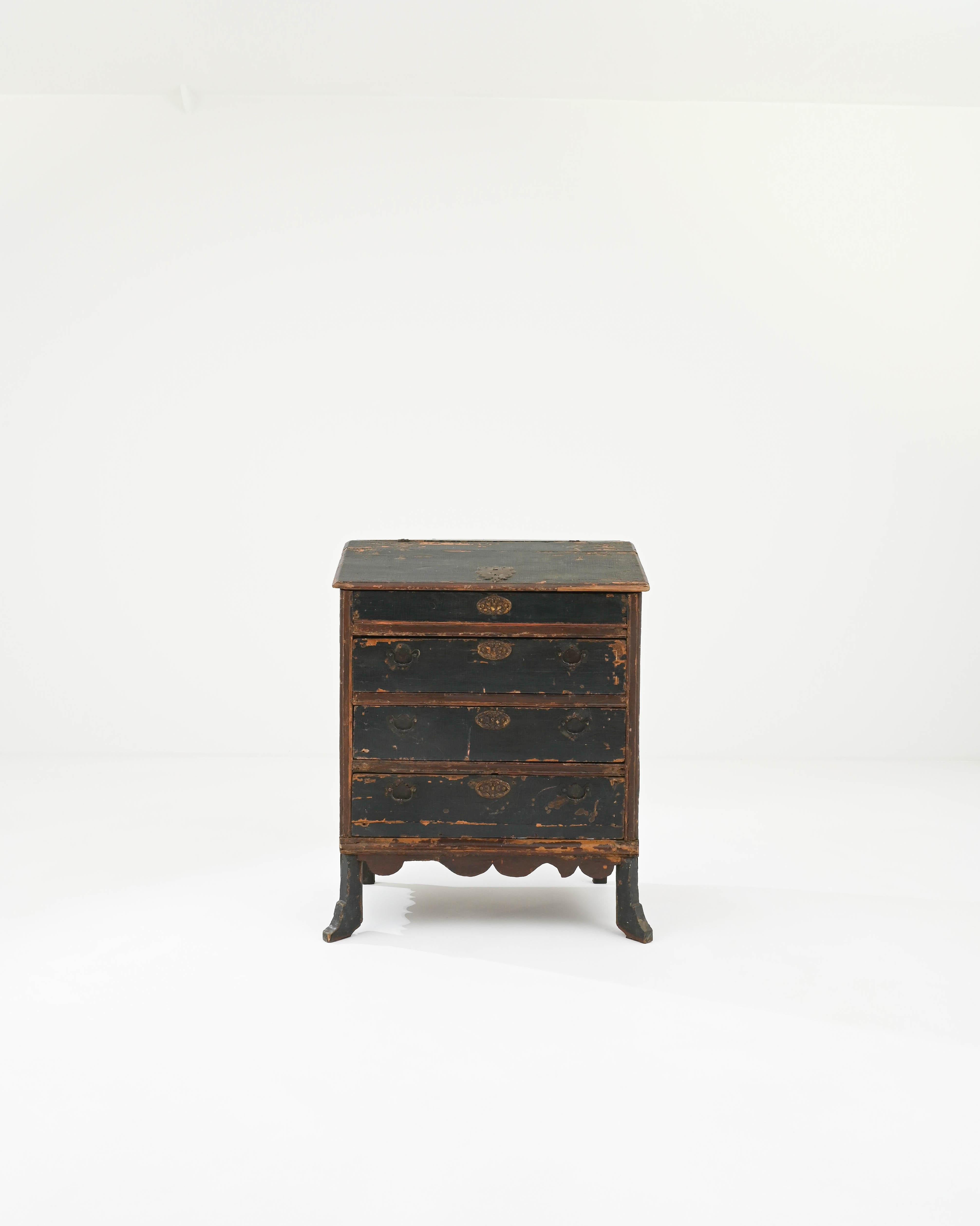 The appealing shape and unique patina of this antique wooden chest of drawers make it a covetable find. Built in Portugal in the 1800s, the gentle tilt of the upper surface suggests that this piece was once used as a writing desk; the lid of the