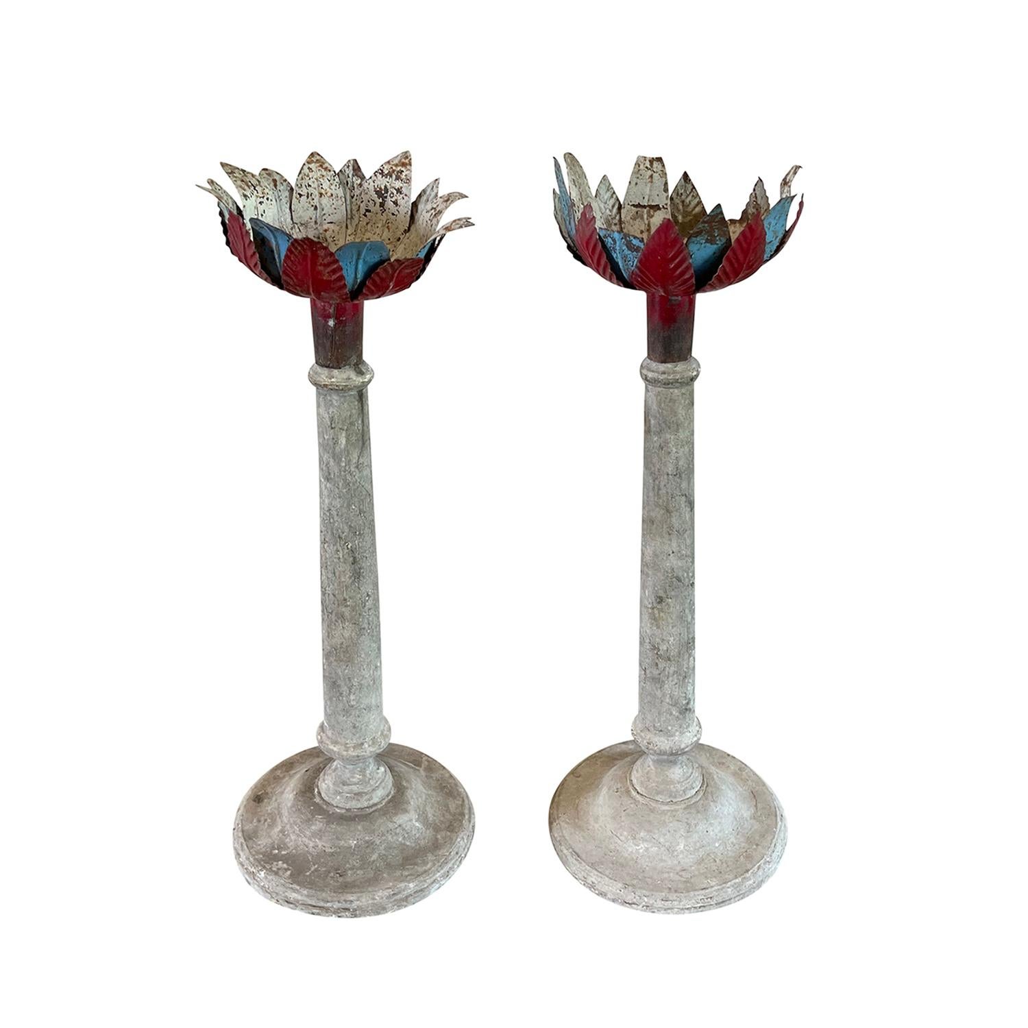 An antique Portuguese pair of 19th Century candle stick holders with a simple Pinewood structure on a round circular base, in good condition. The finely hand crafted metal plates are made of staggered oxblood red and vibrant blue leaved. Original