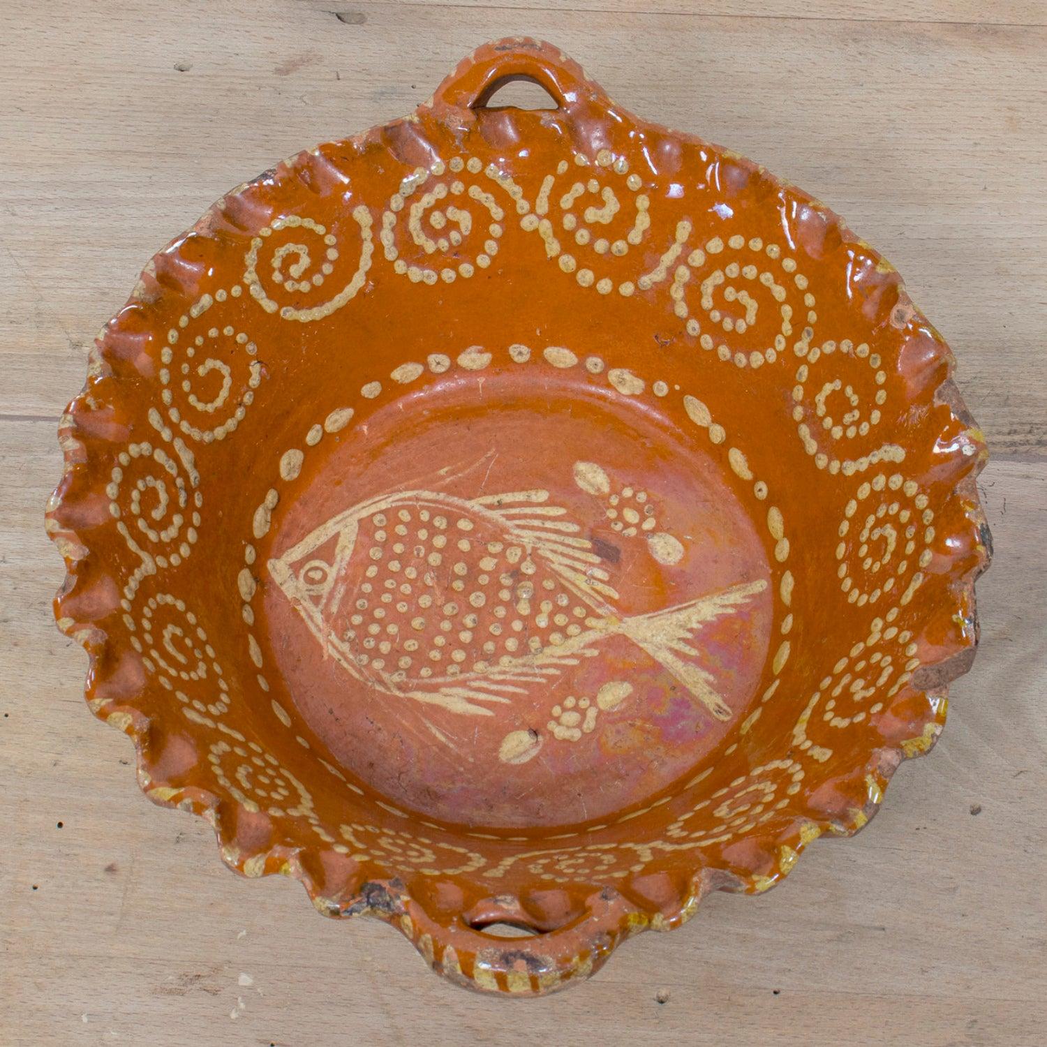 A delightful example of 19th century Portuguese folk pottery, this hand-thrown red slipware bowl showcases the rustic charm and vibrant artistry of rural Portugal. Crafted from terracotta and finished with a glossy red slip glaze, the bowl features