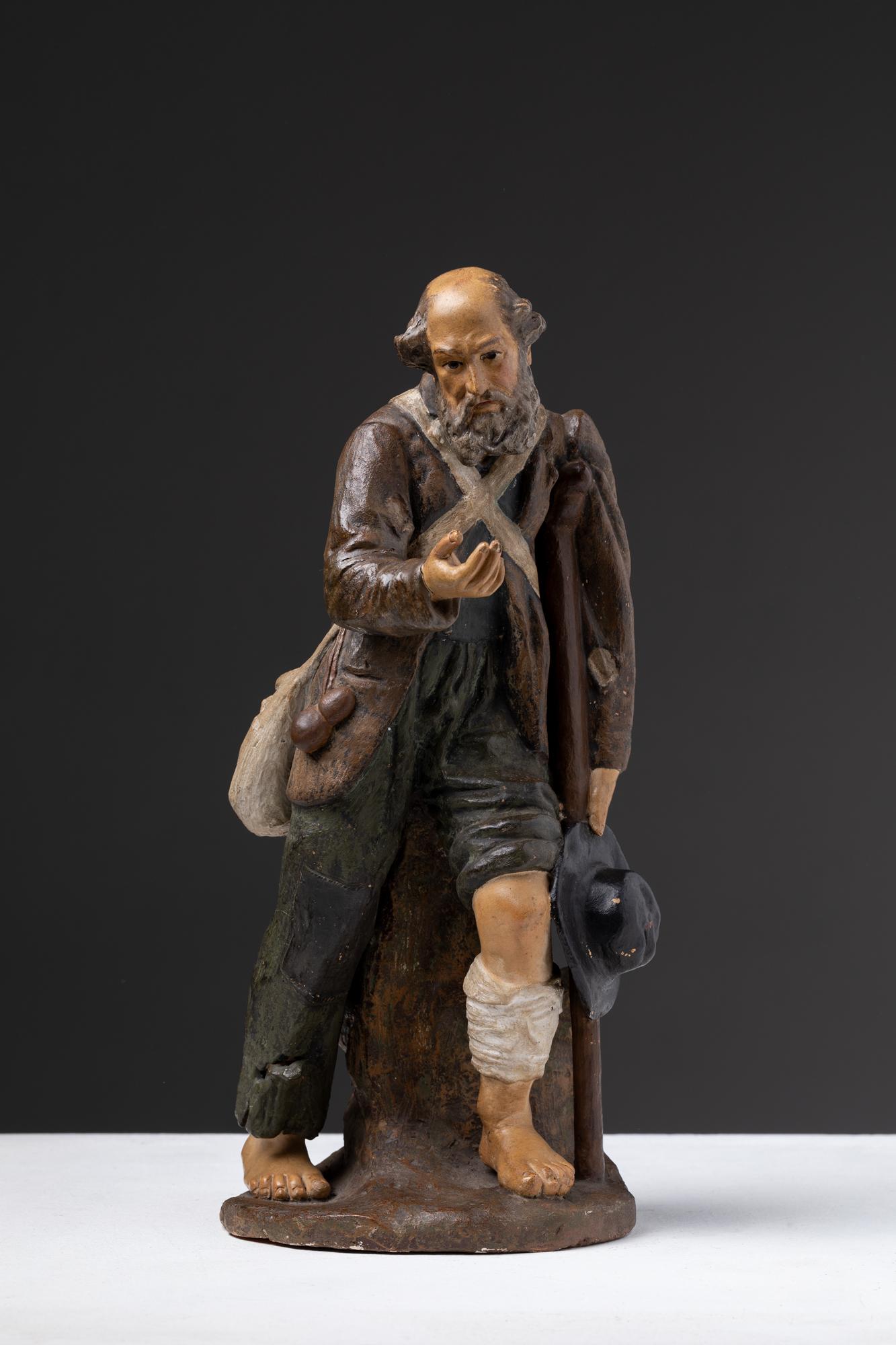 Questa scultura in terracotta portoghese del XIX secolo rappresenta un mendicante e forse deriva da un presepe (presépio). L'opera riflette la ricca tradizione dell'arte religiosa e popolare portoghese, dove le statuette venivano spesso realizzate a