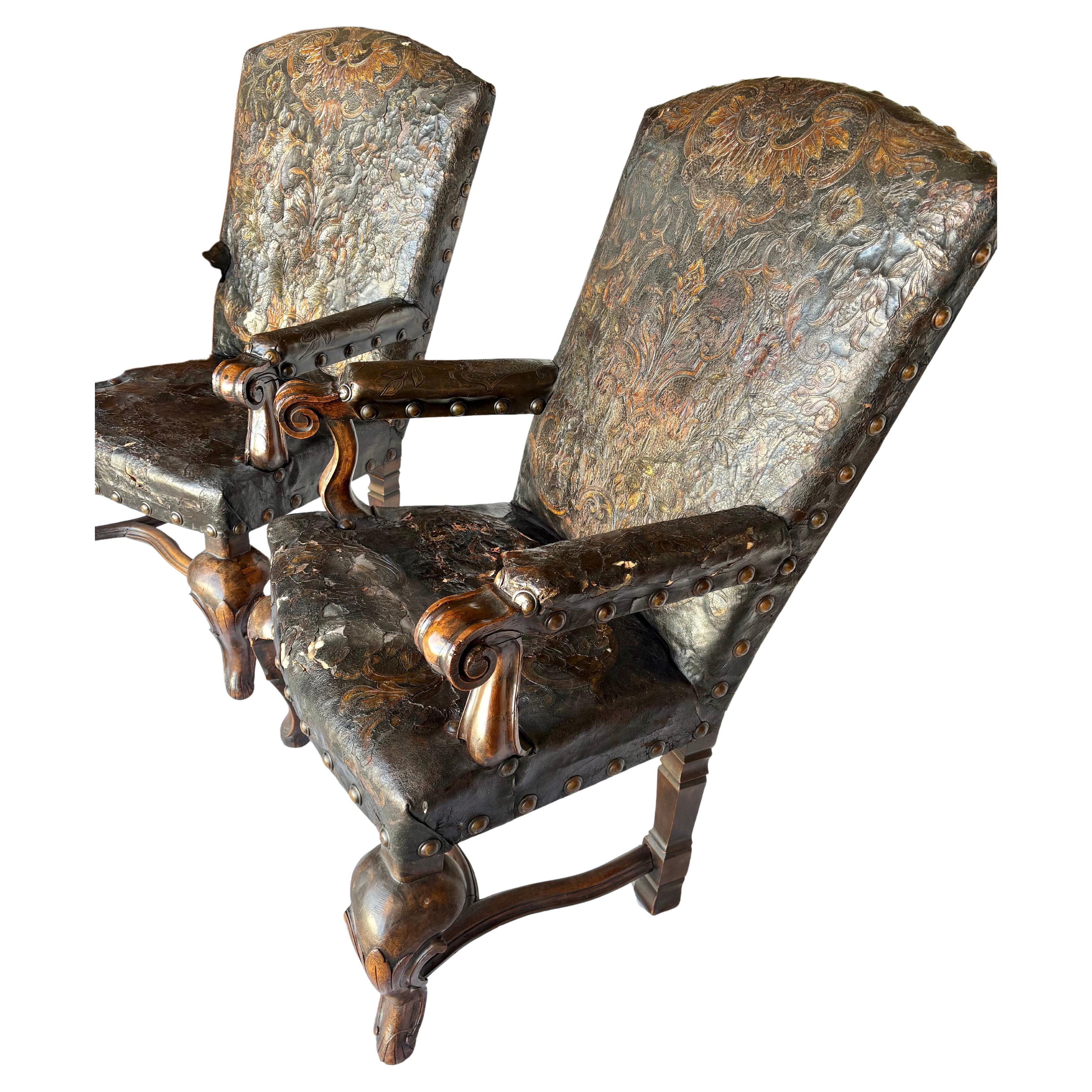 Questa grande coppia di poltrone portoghesi del XIX secolo è stata realizzata in noce vecchio e pelle all'inizio del 1800. Le sedie presentano l'originale rivestimento in pelle goffrata che è stato fissato a mano con ottone invecchiato. Ogni braccio