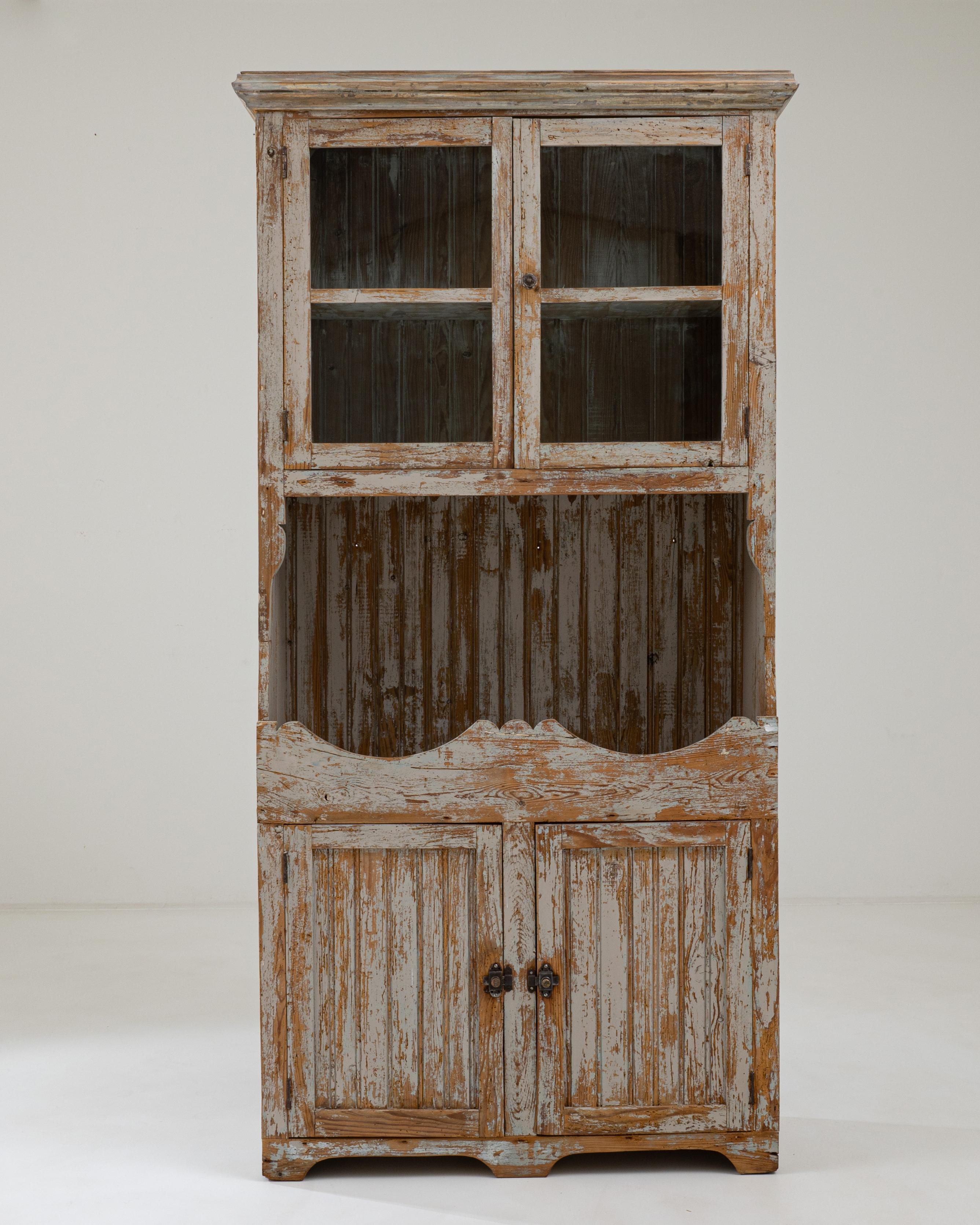 A wooden vitrine created in 19th century Portugal. With a traditional farmhouse aesthetic, this Portuguese display cabinet radiates a pleasant familiarity and warmth. Over the course of its journey, the gray paint has slowly ebbed away to reveal the