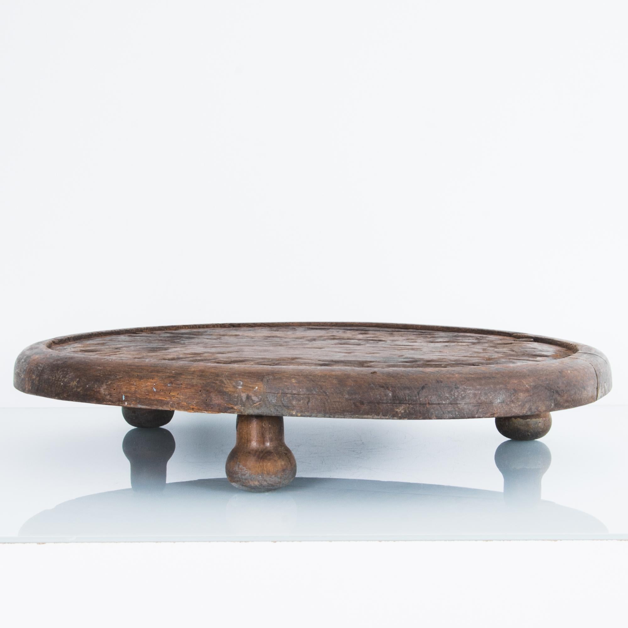 This primitive oak tray comes from France, circa 1880. Three button legs provide humble elevation, and the dark finish of the oak lends the piece a certain solemnity. The erosion of the surface speaks to the long history of this rustic antique tray.
