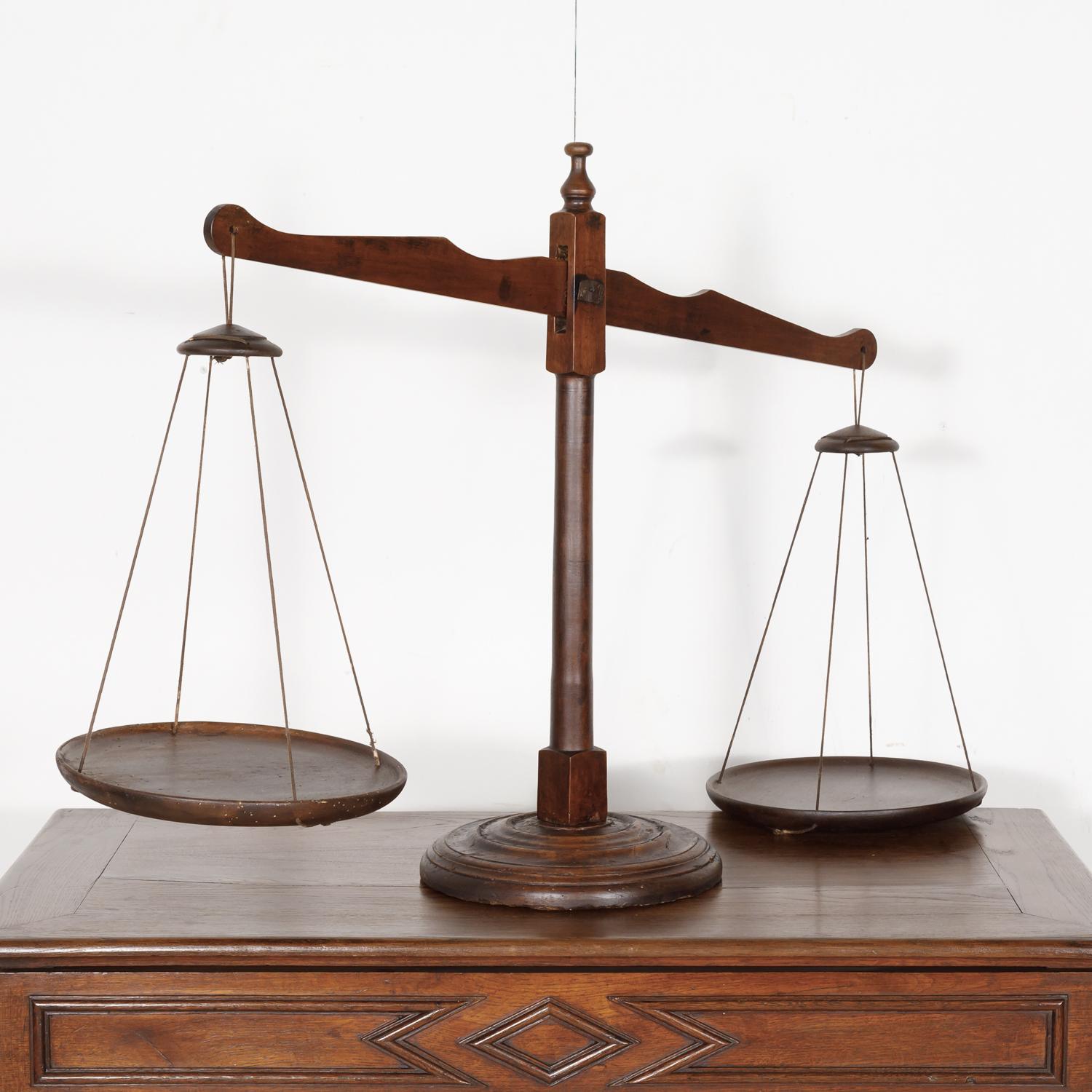 A handsome 19th century primitive French balance scale hand carved of solid walnut. The wood pans are attached with leather cording. A very versatile and decorative piece, it would look lovely in a kitchen, on a stack of books, or a table. Many