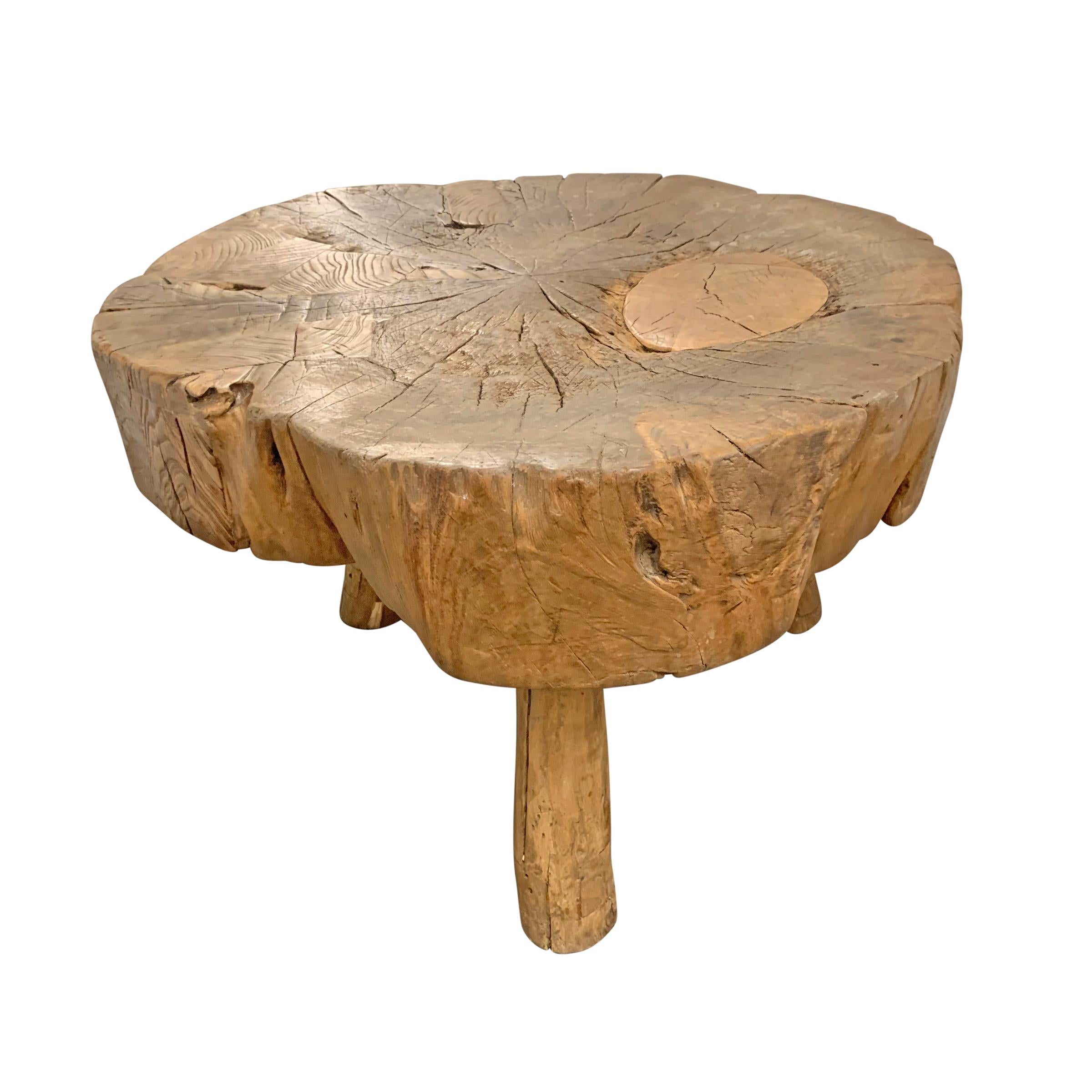 A wonderful primitive table constructed from a slice of a tree trunk and supported on three legs, with lots of personality, several patches, and a beautiful patina.