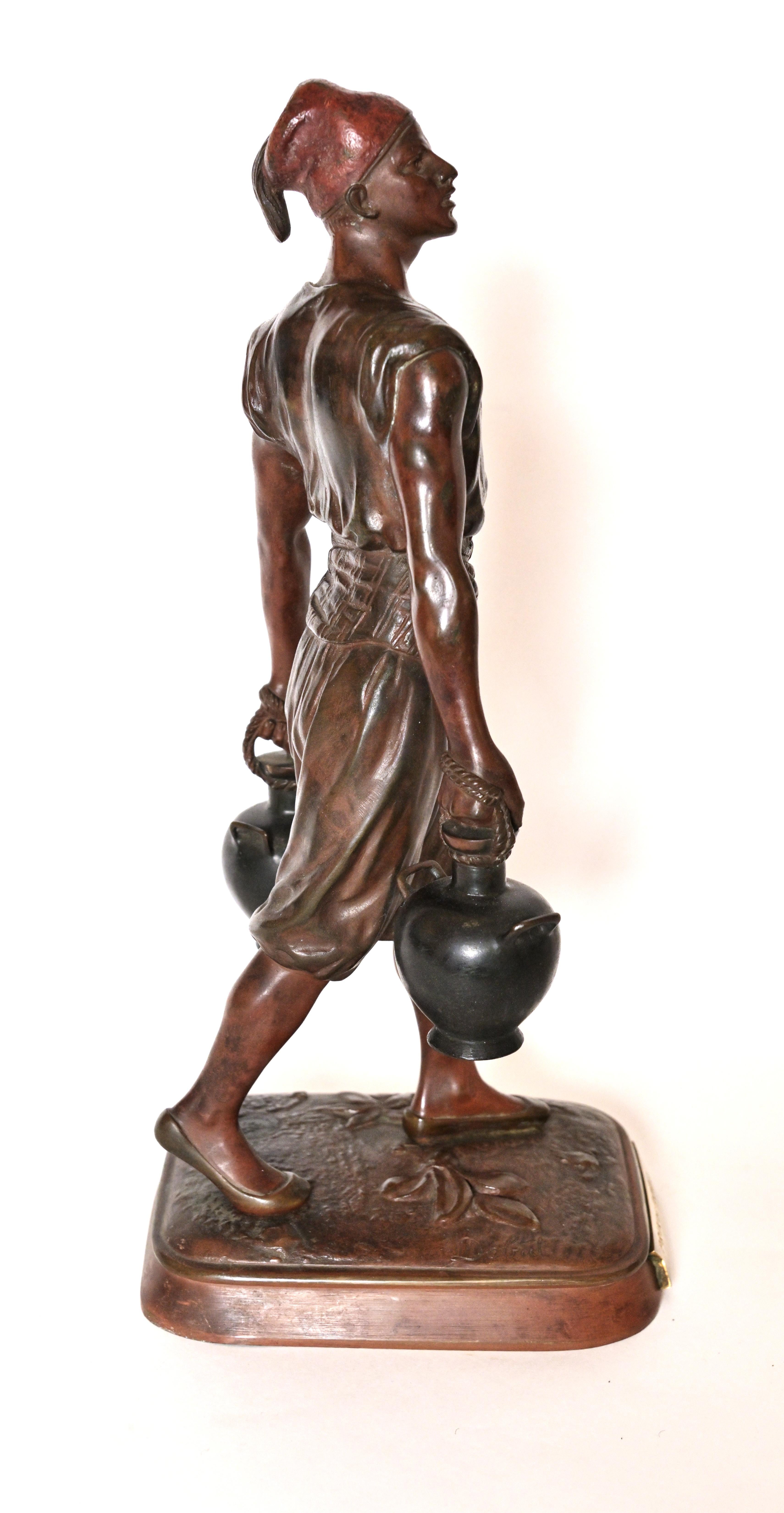 A 19th century French Bronze depicting a Moroccan Male wearing a fez and carrying two jugs of water. Base is labeled with 