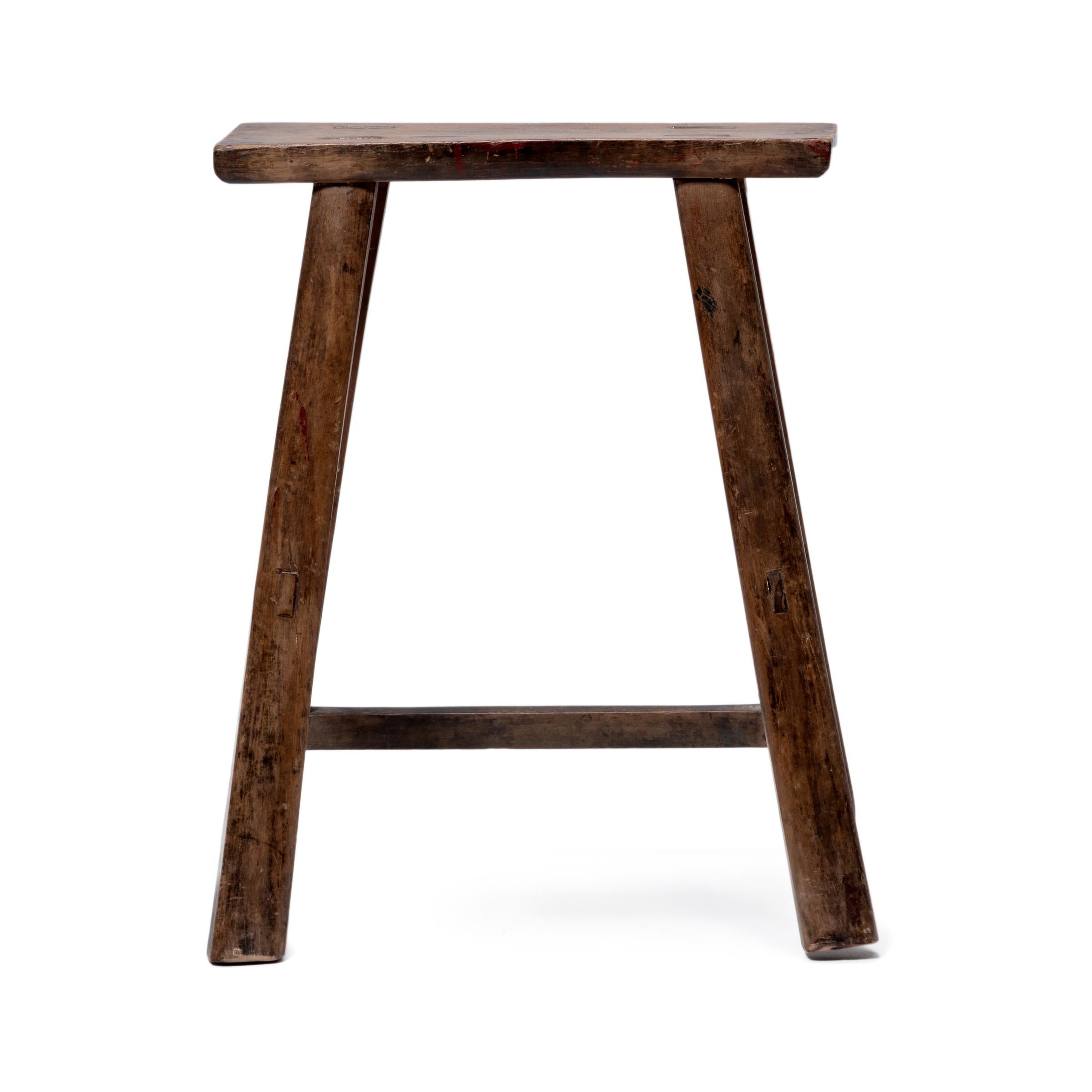 This 19th century elmwood stool from China's Shanxi province features a narrow seat supported by splayed legs, linked with simple stretcher bars. The stool was constructed with mortise-and-tenon joinery techniques, without the use of nails or