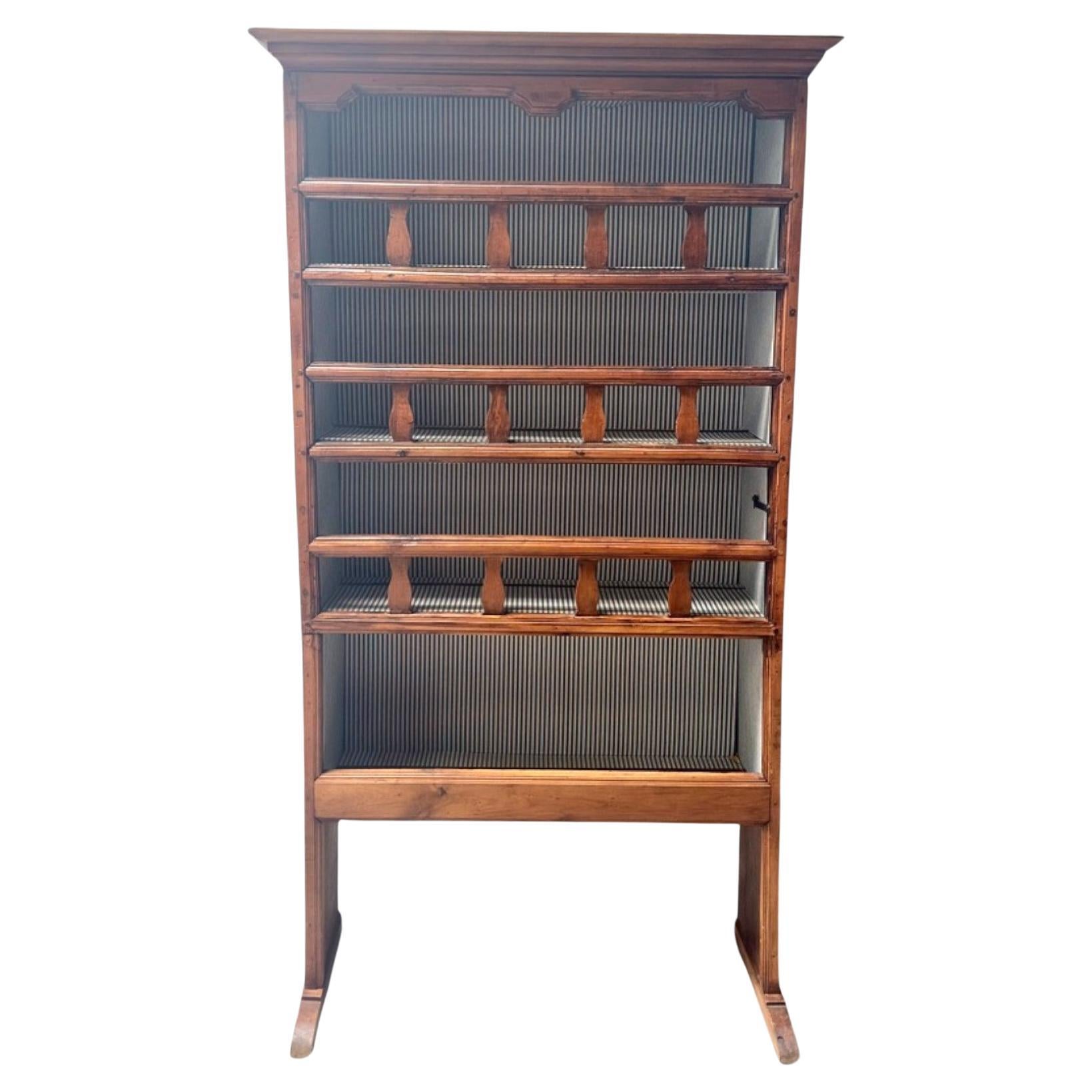 Cette charmante huche de cuisine provinciale du XIXe siècle présente un design classique de porte-assiettes, avec cinq étagères encadrées par des barres de bois rustiques, parfaites pour présenter et organiser les assiettes. La façade est articulée