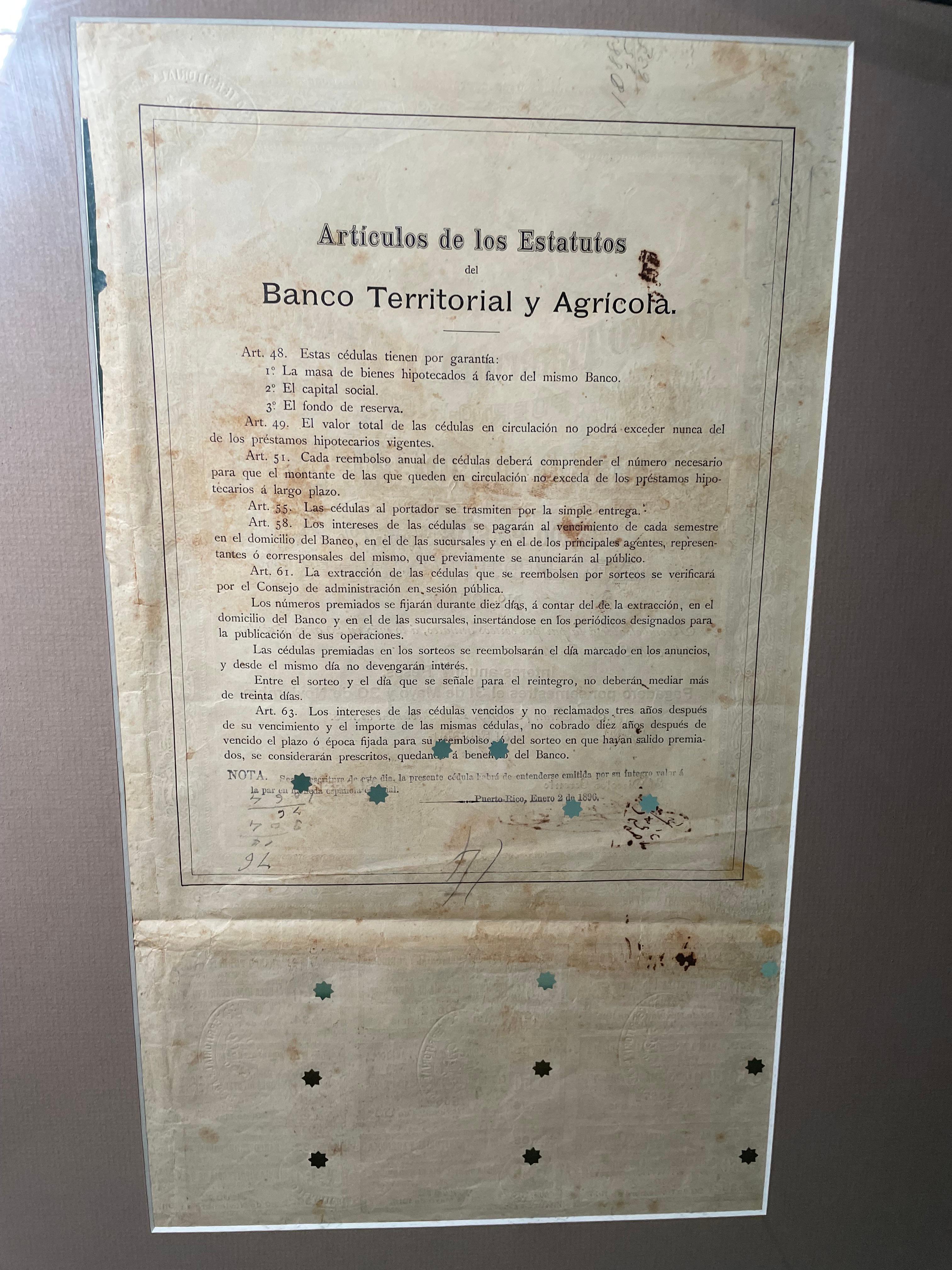 Si tratta di un certificato ipotecario del XIX secolo proveniente da Porto Rico, quando l'isola era una colonia spagnola. Raffigura il certificato di ipoteca della Puerto Rican Agricultural and Territorial Bank montato in una stuoia e in un cartone