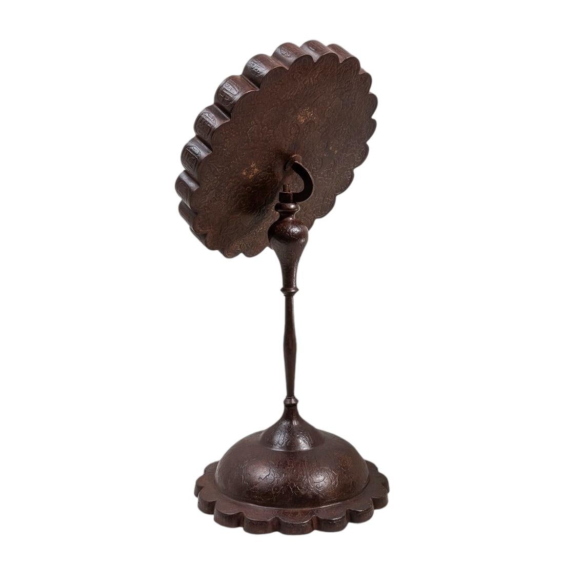 Antique (19th century) Qajar dynasty period tabletop boudoir mirror with rust brown patina and inlaid gold, 21 1/4 inches tall.  Chased and repousse designs including a face at center in relief, original hinge and latch revealing its original