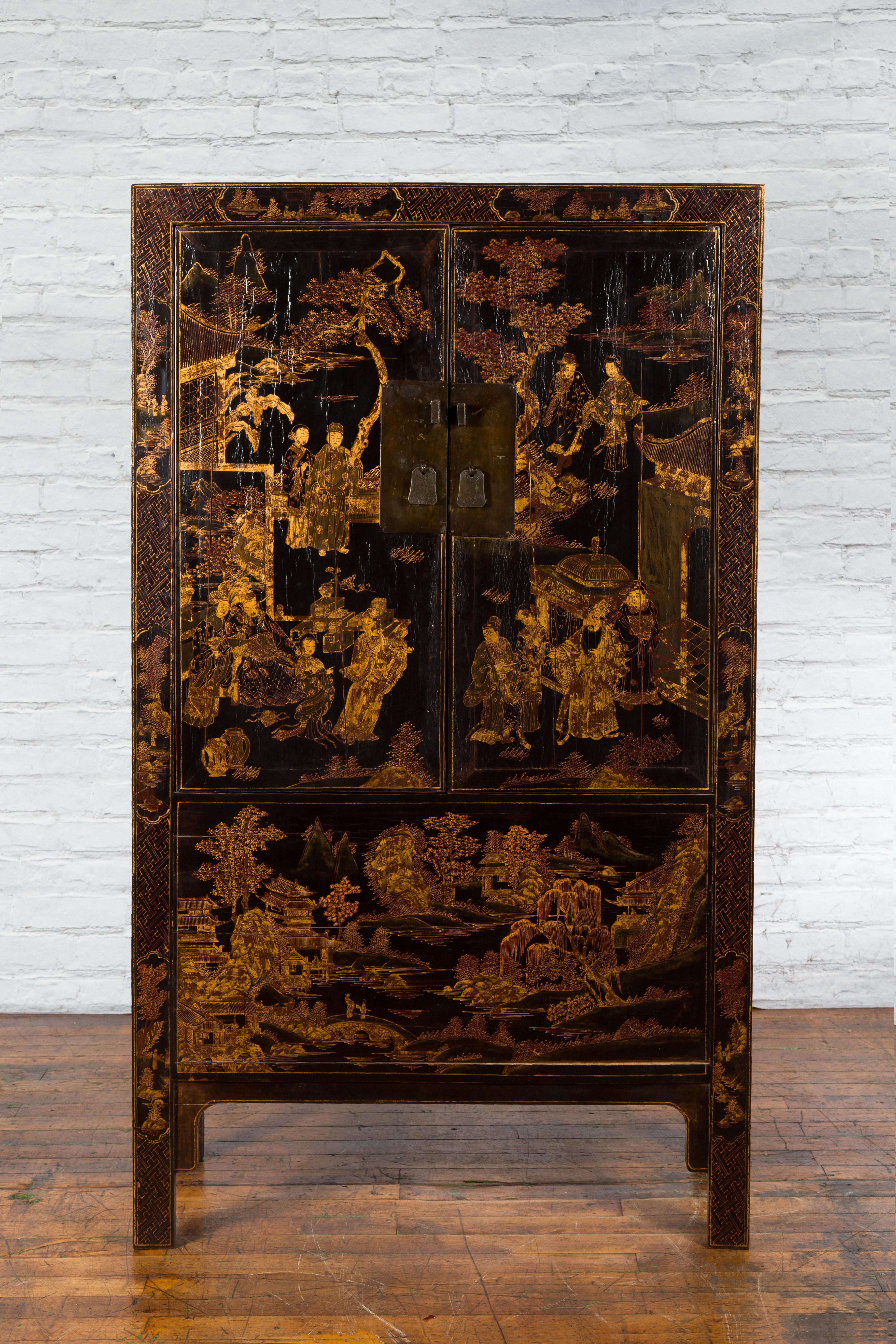 A Chinese Qing Dynasty period black lacquered cabinet from the 19th century, with gilt Chinoiserie décor and hidden drawers. Created in China during the Qing Dynasty era, this cabinet features a black lacquered ground beautifully adorned with a
