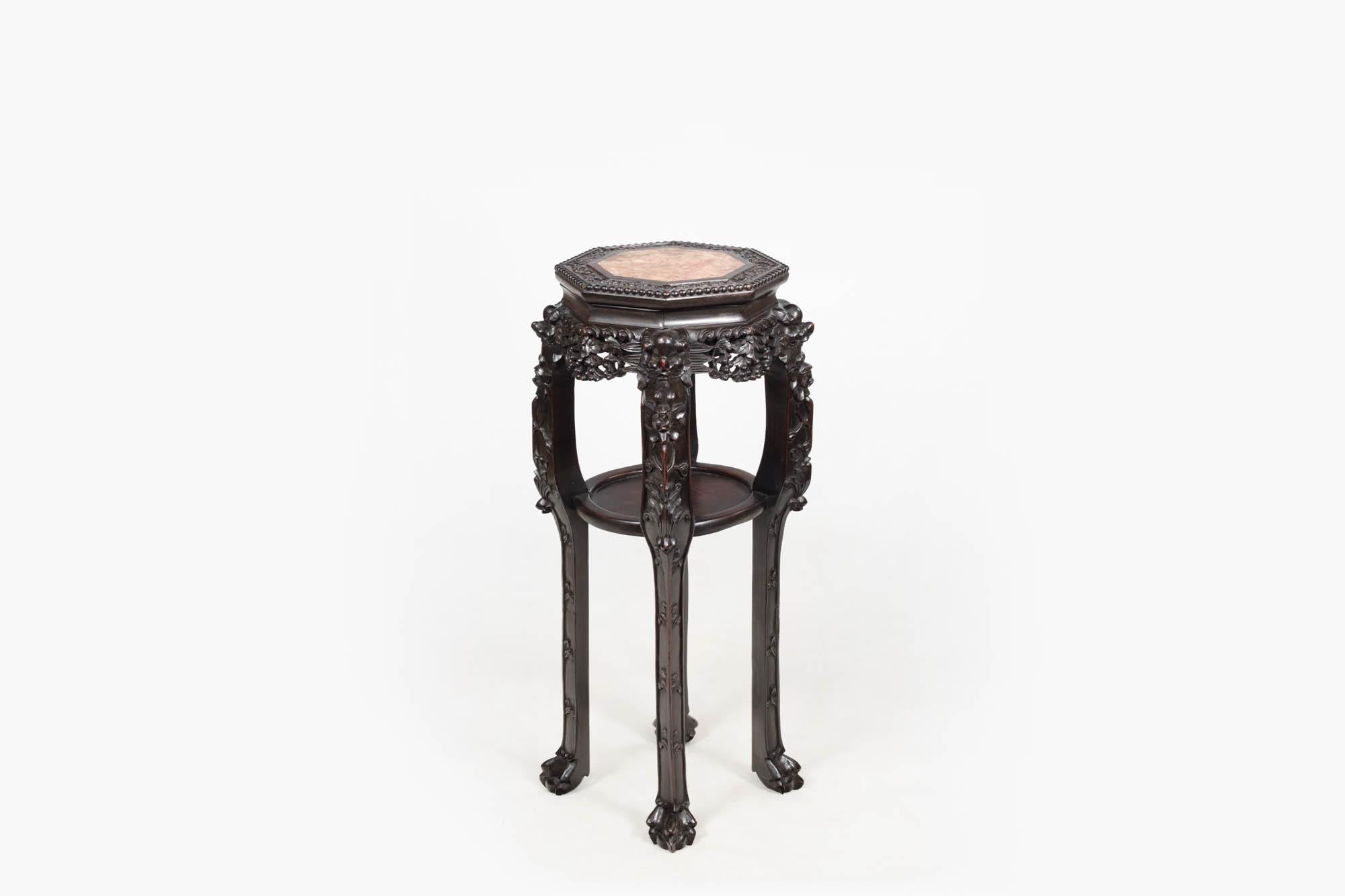 19th century Qing Dynasty Chinese cherrywood pedestal plant stand. The highly carved top features floral relief, and beaded trim and is inset with pink marble. There is a simple round inner center shelf and the piece is raised on four carved