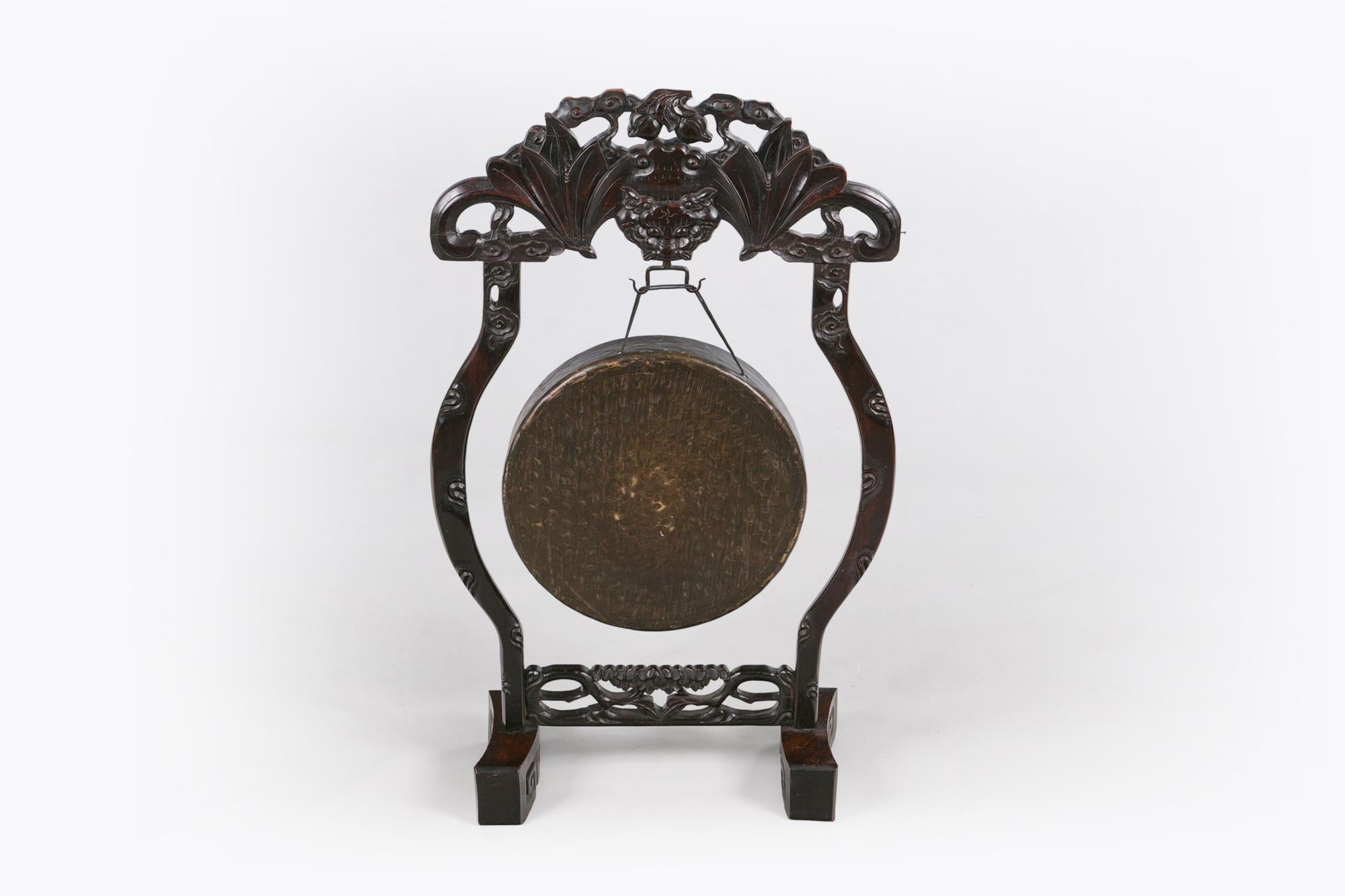 19th century Chinese Qing dynasty hand forged brushed bronze ceremonial temple gong of circular form mounted on ornately carved cherrywood stand. The finely carved and pierced hardwood frame surmounted with foliate cartouche raised over suspended