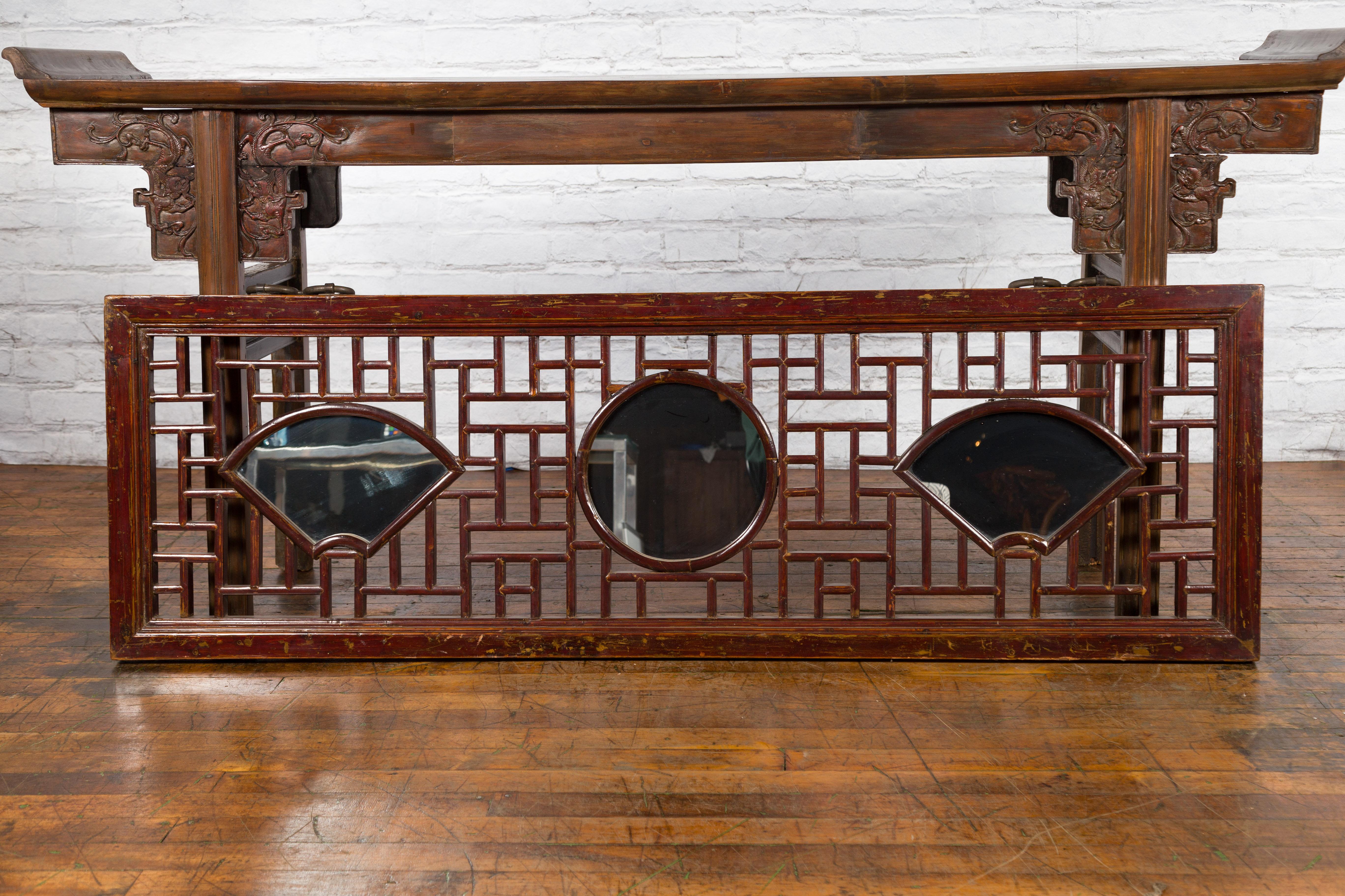 A Chinese Qing Dynasty period three-panel horizontal elmwood mirror from the 19th century, with fretwork and fan shaped motifs. Created in China during the Qing Dynasty, this 19th century elmwood panel is adorned with fretwork motifs surrounding a