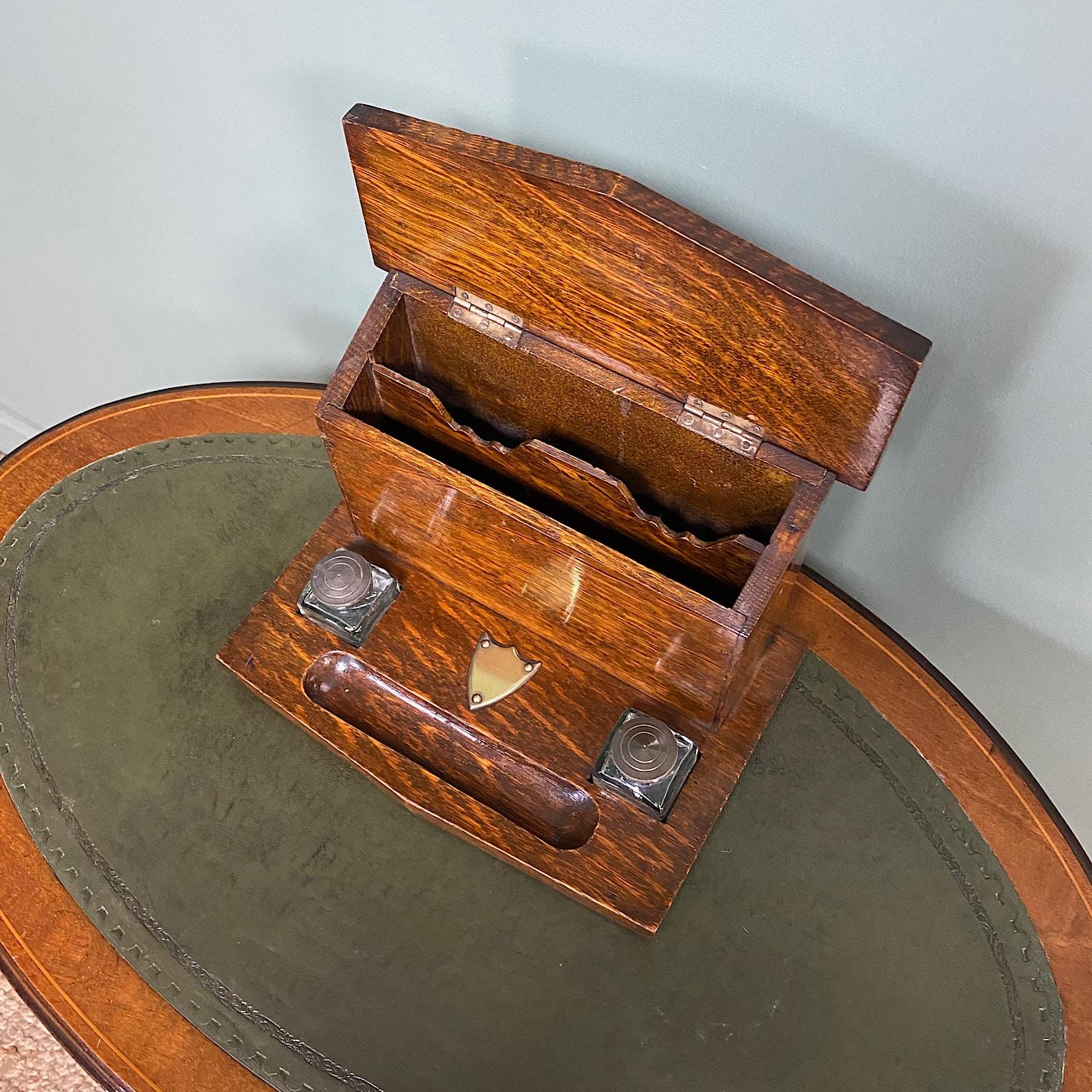 Quality Victorian Oak Antique Stationary Box

This Victorian Oak Desktop Stationary Box has an up-stand with lift up lid with decorative plaque and the interior has a shaped divide for letter storage. The base has a pen holder and inkwells. The