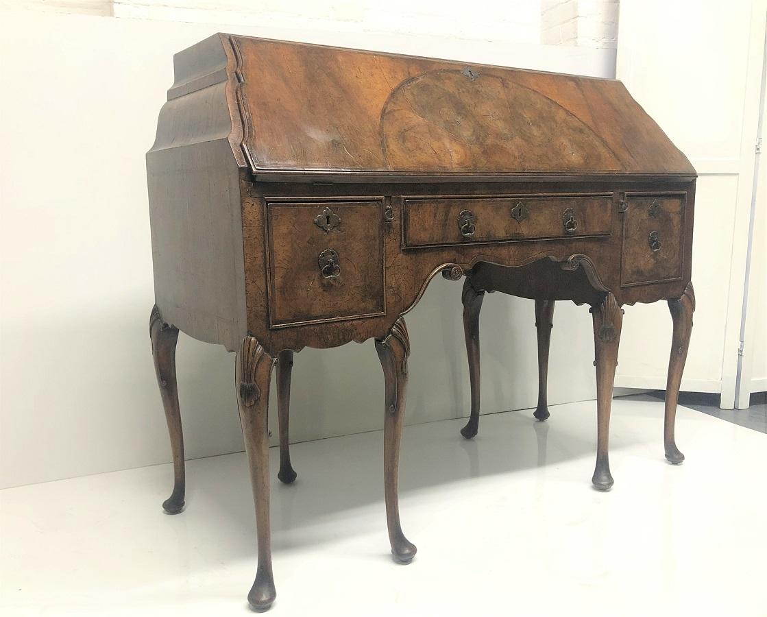 Segreteria intarsiata in noce in stile Queen Anne del XIX secolo con fronte inclinato. L'interno della segretaria presenta gli specchi al mercurio originali e i cassetti hanno code di colomba tagliate a mano ai lati e sul retro dei cassetti. Ha