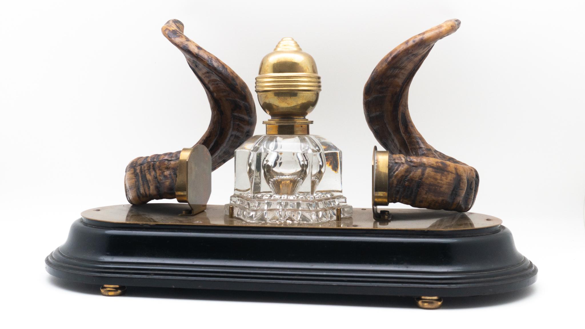 19th century ram's horn decorated inkwell, possibly Scottish. Comprised of a brass topped glass inkwell mounted on a brass and wooden oval base.