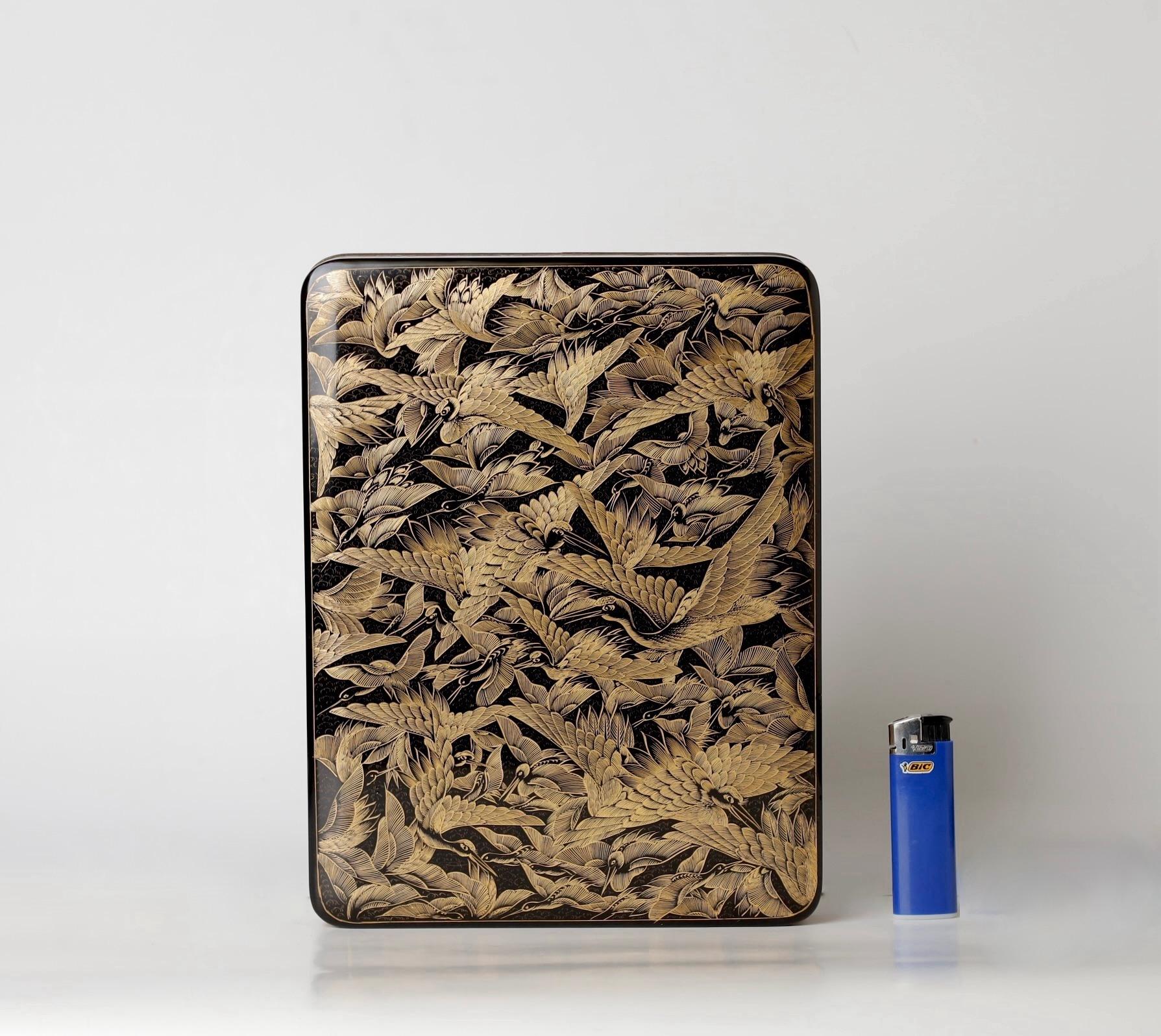 Boîte finement laquée avec un motif incisé, rempli d'or. 
Remarquable boîte laquée du 19e-20e siècle, décorée de grues volantes.  

Sa forme unique allie l'artisanat traditionnel à de subtiles influences Art déco. La surface laquée noire lustrée est