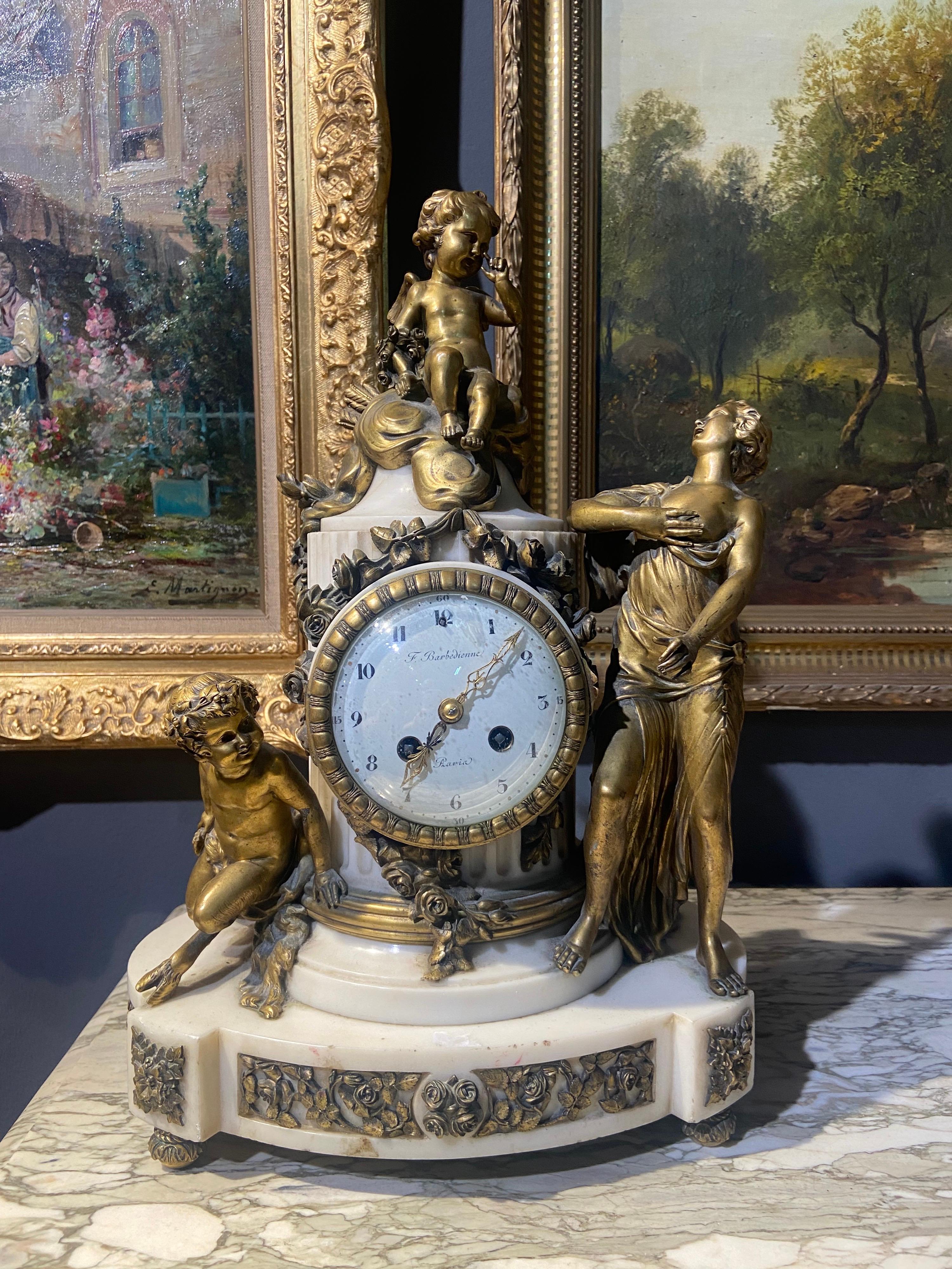 French mantel clock by Ferdinand Barbedienne consisting of a terminal clock in the form of a fluted column in white marble and decorated with three figures in gilded bronze: satyr child, putto and young woman; the dial signed F. Barbedienne Paris.