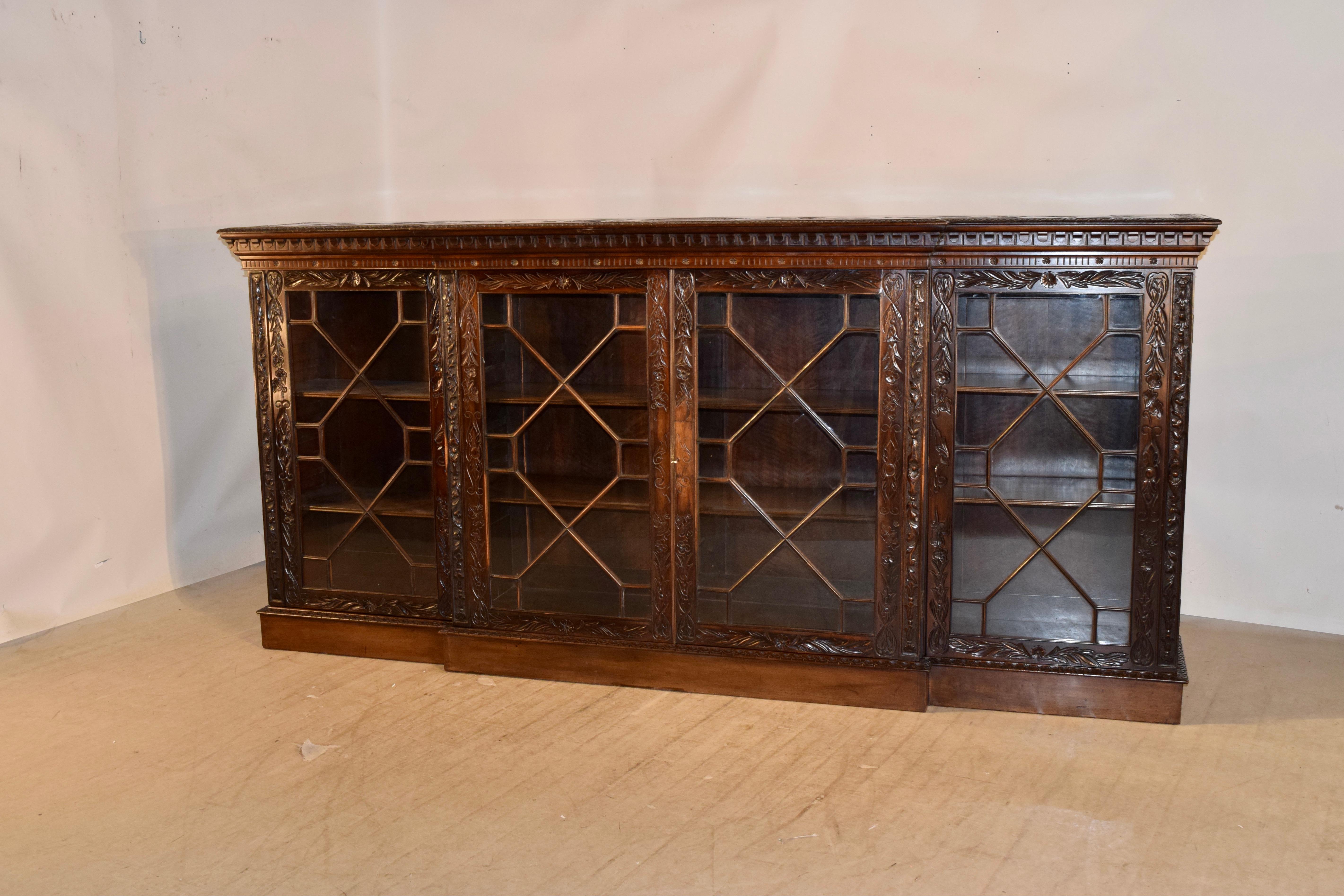 19th century rare and unusual hand carved mahogany bookcase from England. The top has a banded edge which is hand carved decorated and also has a beveled and carved edge around the top. The central design on the top is framed with this banding and