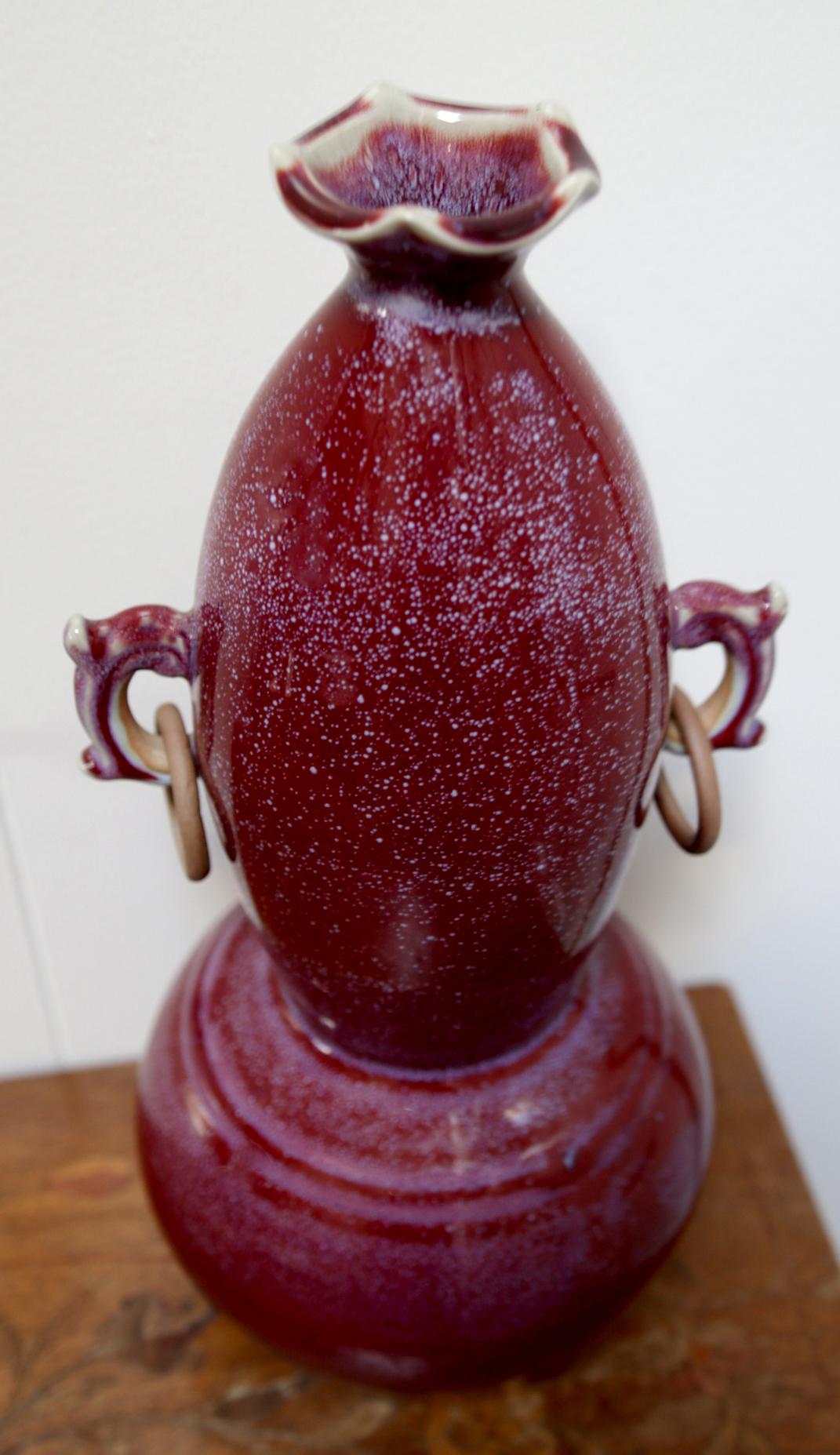 From the antique brass oxidized copper rings that hang from the ears, to the gourd shape and body, this is a wonderful example of a highly collectible sang de boeuf, oxblood vase. 
      A late 19th century (circa 1890s) Chinese copper red-glazed