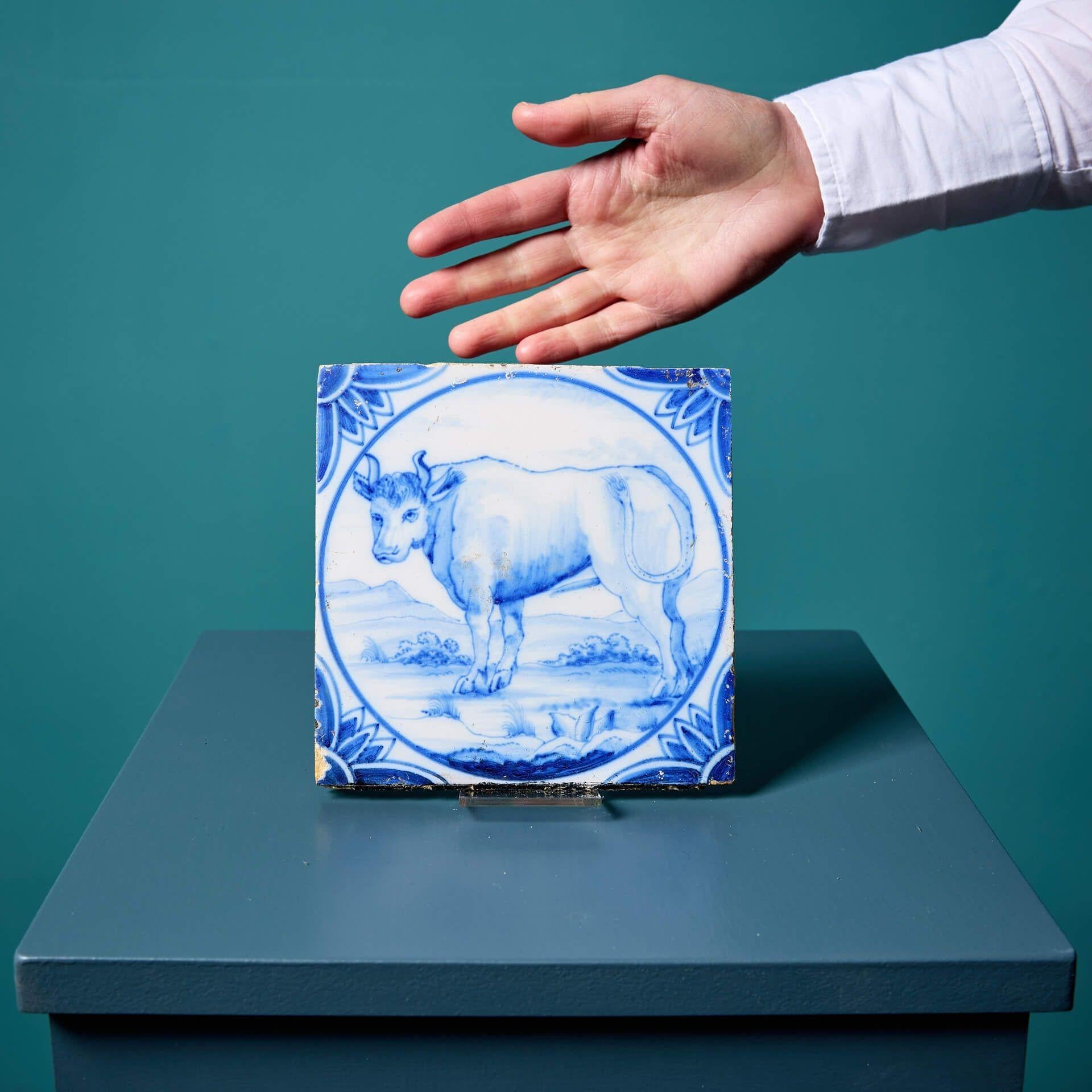 Un ancien carreau de Delft bleu et blanc de 6 pouces représentant un taureau, fabriqué par Ravesteijn d'Utrecht ; l'un des deux carreaux à thème similaire que nous vendons. Ce carreau de cheminée original a été récupéré dans un bâtiment classé Grade