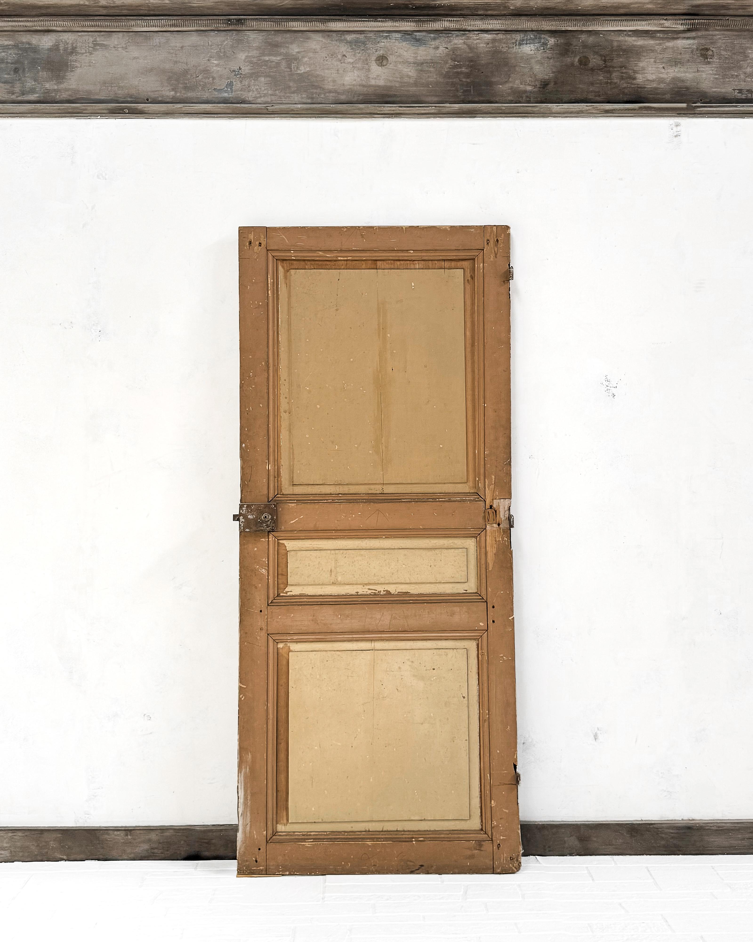 Una porta francese del XIX secolo con tre pannelli rialzati e finiture scanalate e smussate. Installare questa porta in una nuova casa per racchiudere una dispensa o un armadio per la biancheria aggiungerà immediatamente uno strato di charme e