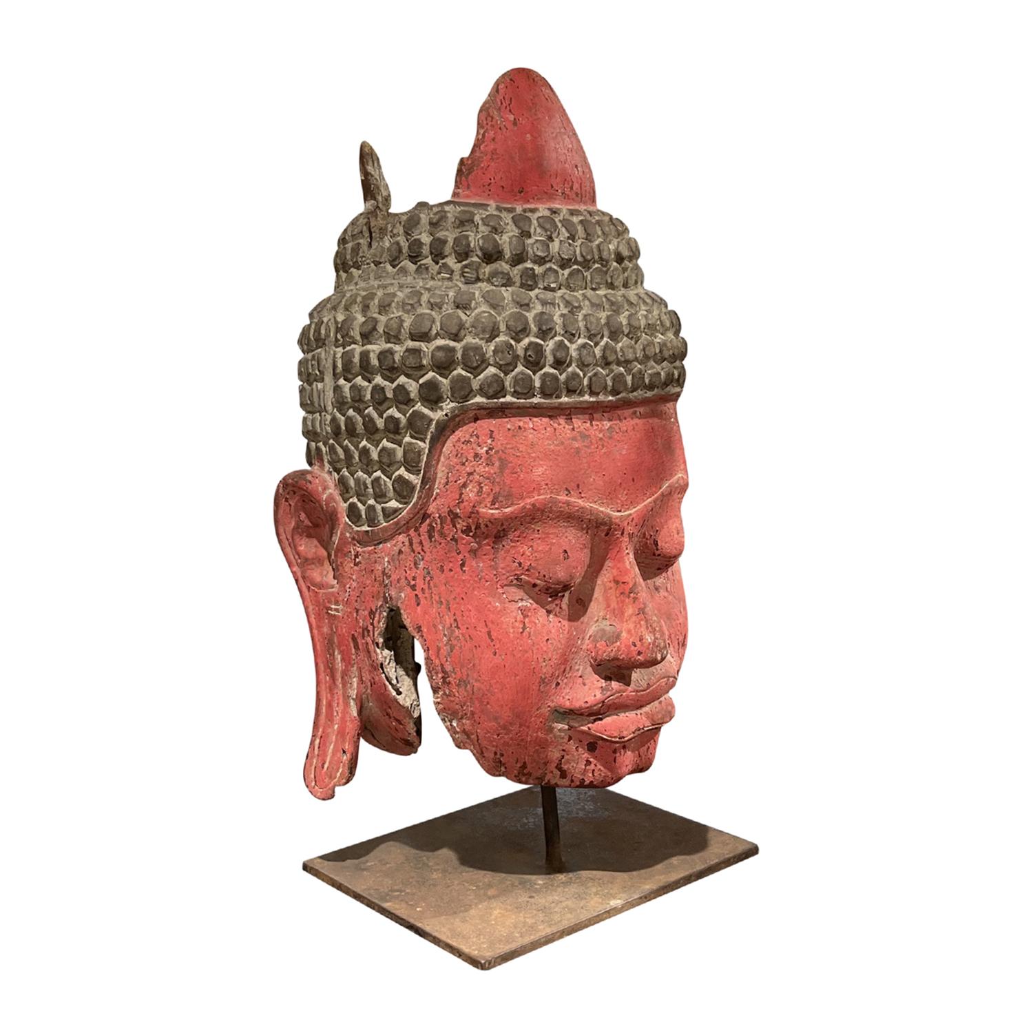 A 19th Century, very decorative large Burmese Buddha head made of hand crafted painted Pinewood, in good condition. The red patinated décor piece is elevated on a square metal base, enhanced by detailed wood carvings. Wear consistent with age and