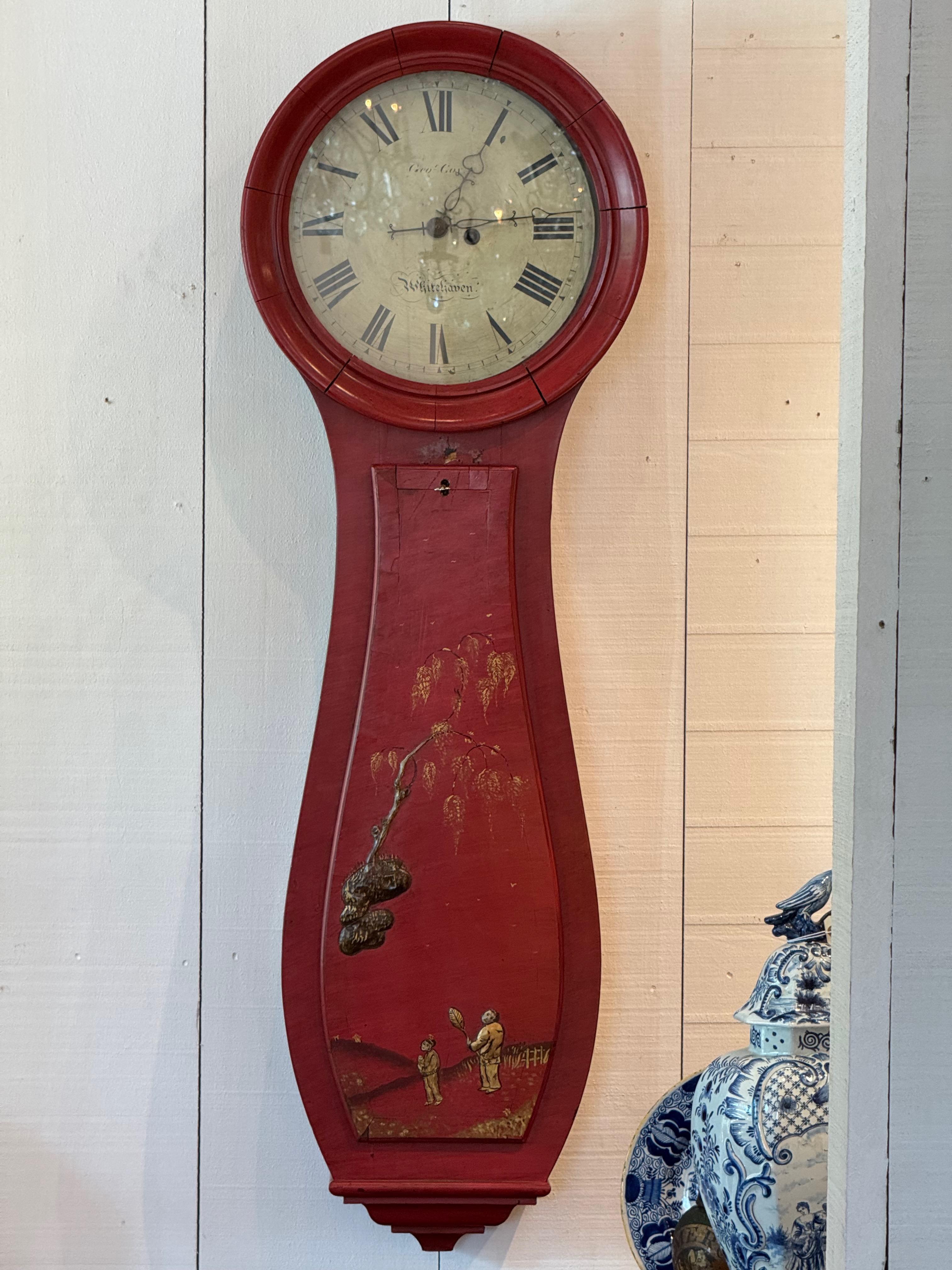 Große, rot bemalte Wanduhr im Chinoiserie-Stil mit handgemalten Figuren und Landschaftsmotiven in Gold und Schwarz. Das gewölbte Gehäuse umschließt ein traditionelles Zifferblatt mit römischen Ziffern und den Unterschriften 