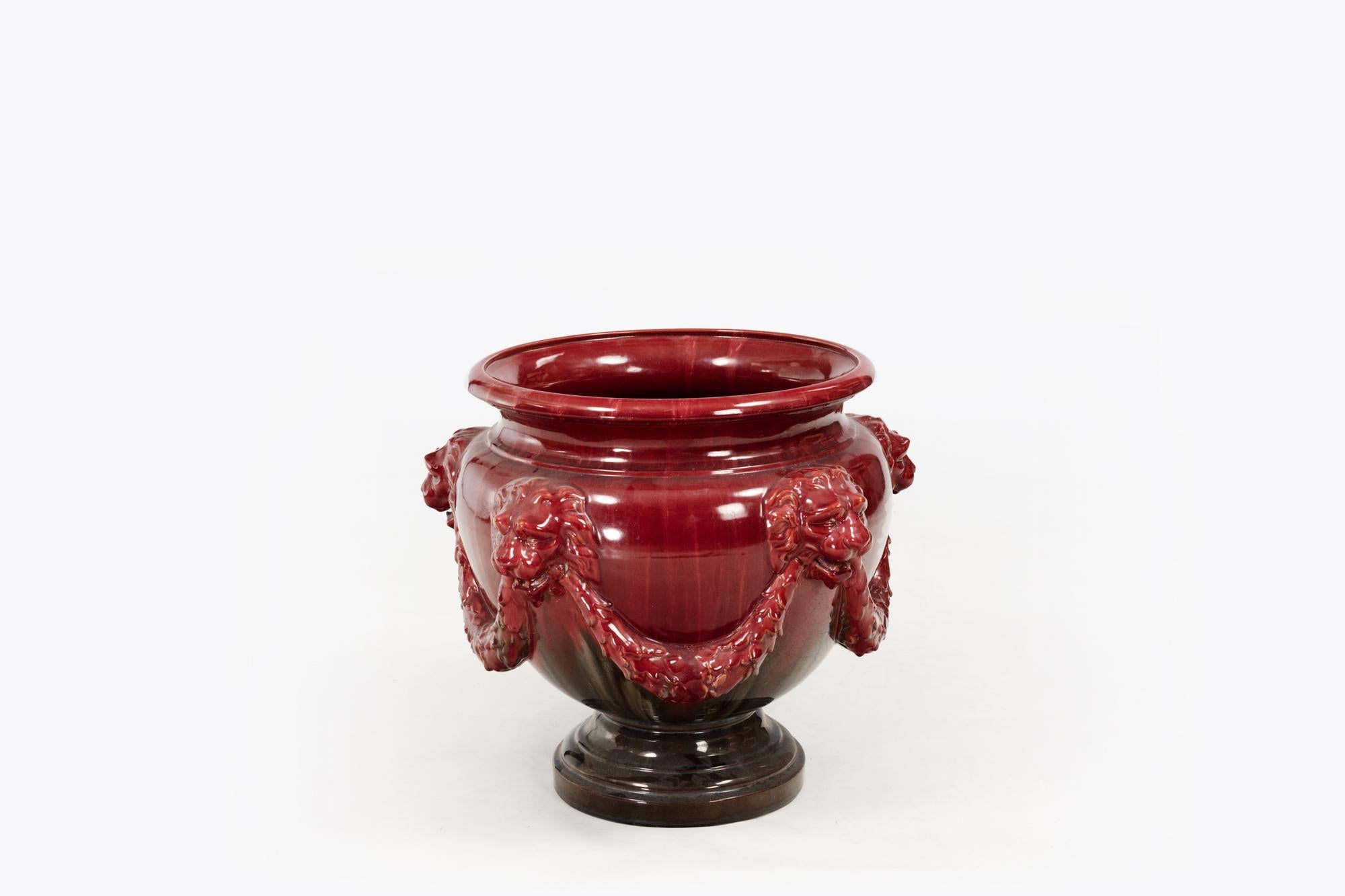 19th Century Jardiniere with lion head masks and garland detailing decorated with blended rich red majolica glaze.