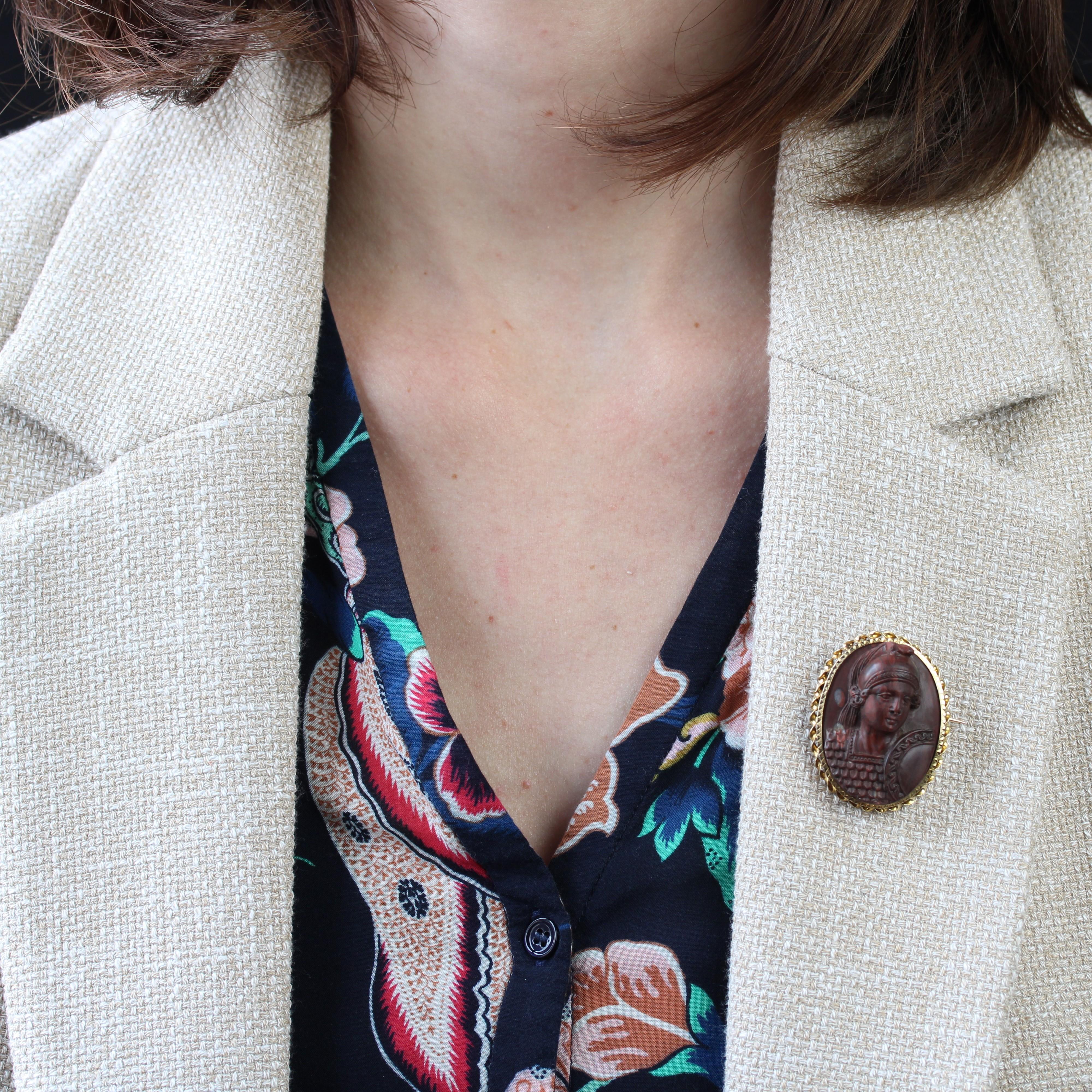 Brooch in 18 karats yellow gold, owl hallmark.
This elegant antique brooch features a cameo on red jasper representing the face and bust of a Roman soldier, his helmet, armor and shield, all finely chased. The closed setting is finely chased and