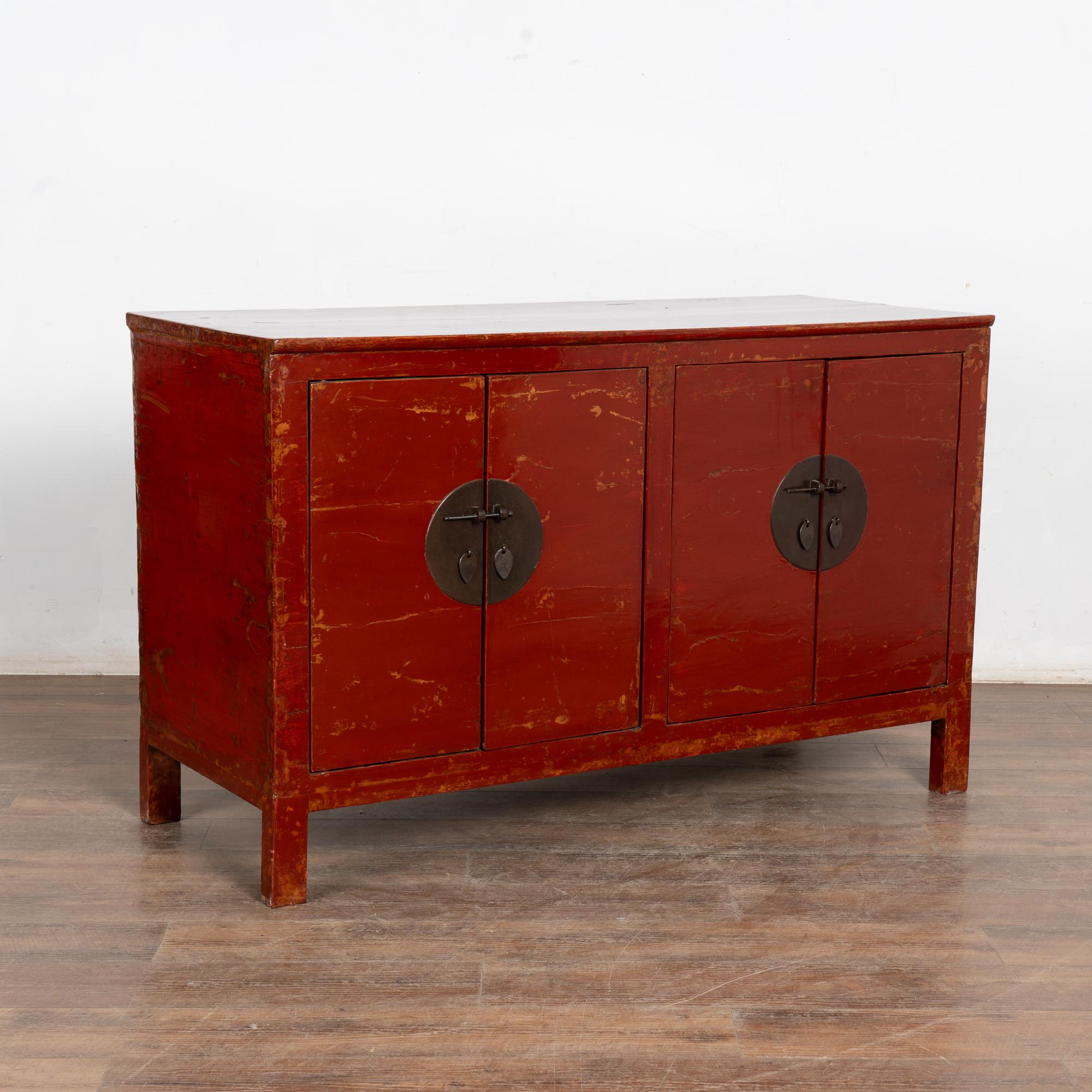 The red lacquered polished finish on this Chinese sideboard or console provides a modern look allowing it to serve well in a contemporary setting. 
The original red painted finish was worn down throughout revealing areas of natural elmwood below,