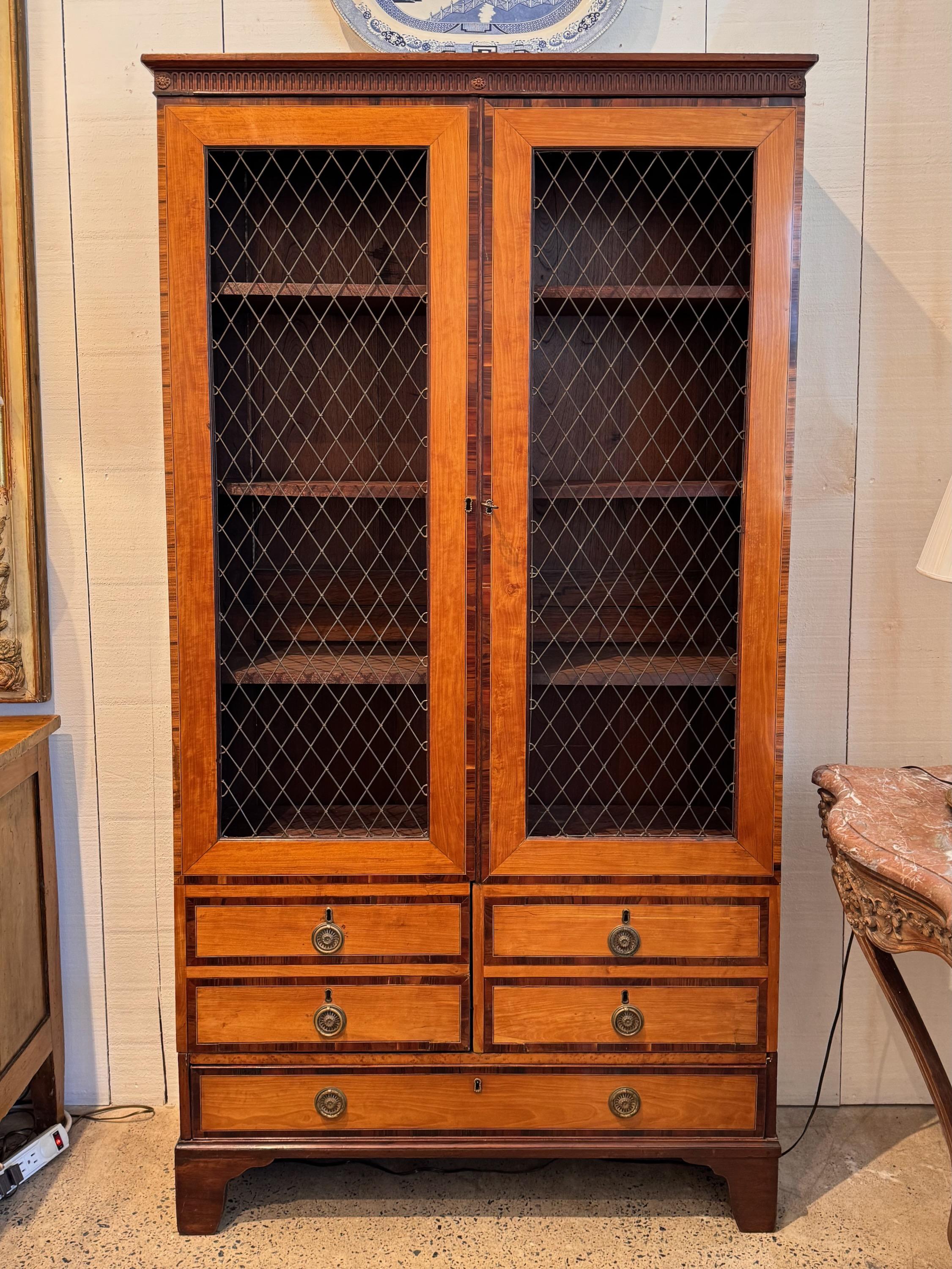 A handsome display cabinet. It has one drawer and brass grill work .