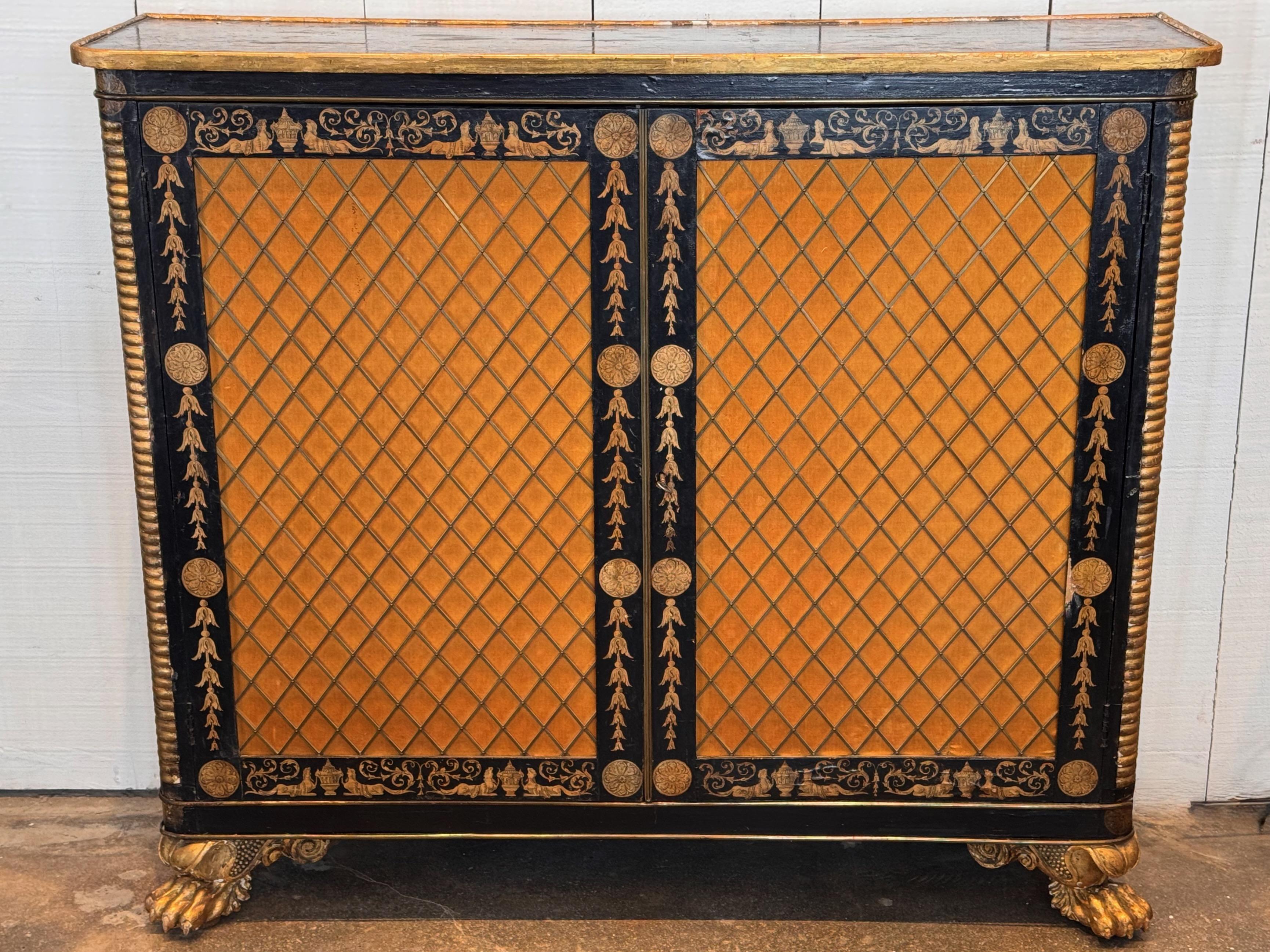 Armadio Regency del XIX secolo con struttura in legno ebanizzato e dorato, con dettagli neoclassici dipinti a mano. Il disegno include urne, fogliame a scorrimento e figure classiche, che riflettono lo stile dell'epoca.

Le porte presentano un