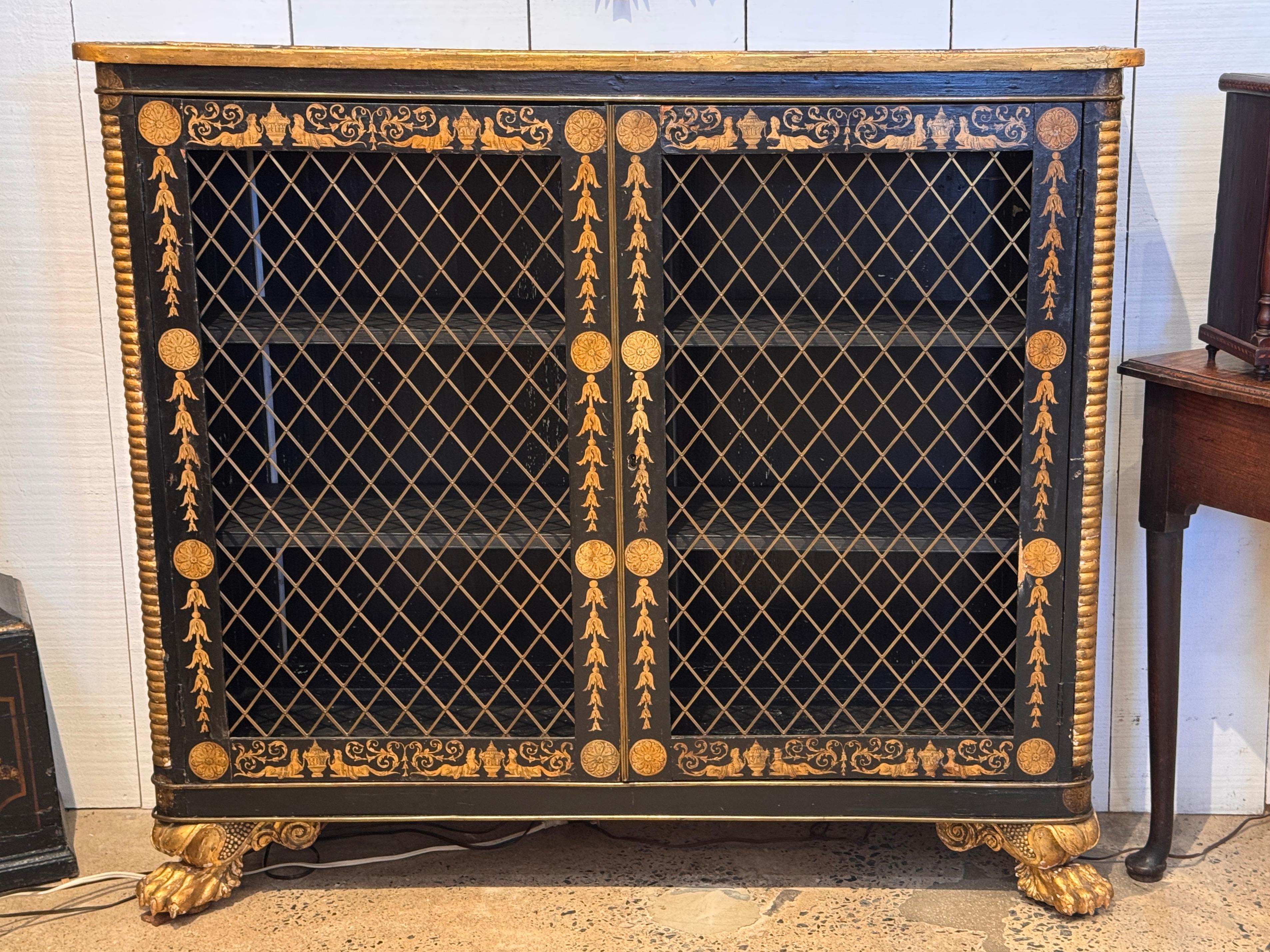 Mobile Regency con decorazioni nere e dorate, porte con griglia in ottone e piedi dorati a zampa di leone. L'ornamento dipinto è mostrato chiaramente nell'immagine di dettaglio della superficie superiore. Interno dotato di tre ripiani