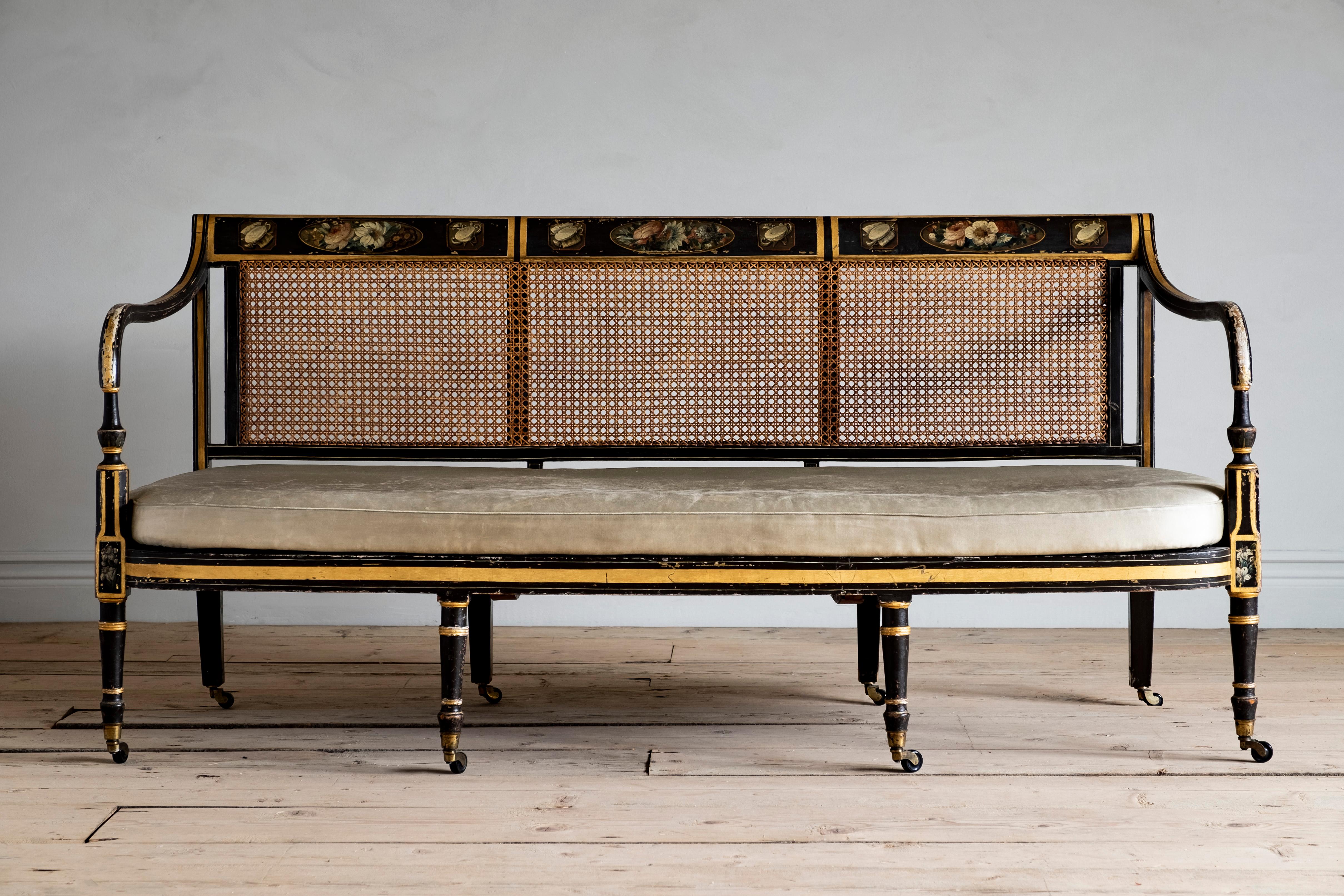 An elegant Regency period painted and caned sofa with turned front legs on casters, circa 1820 England.
     