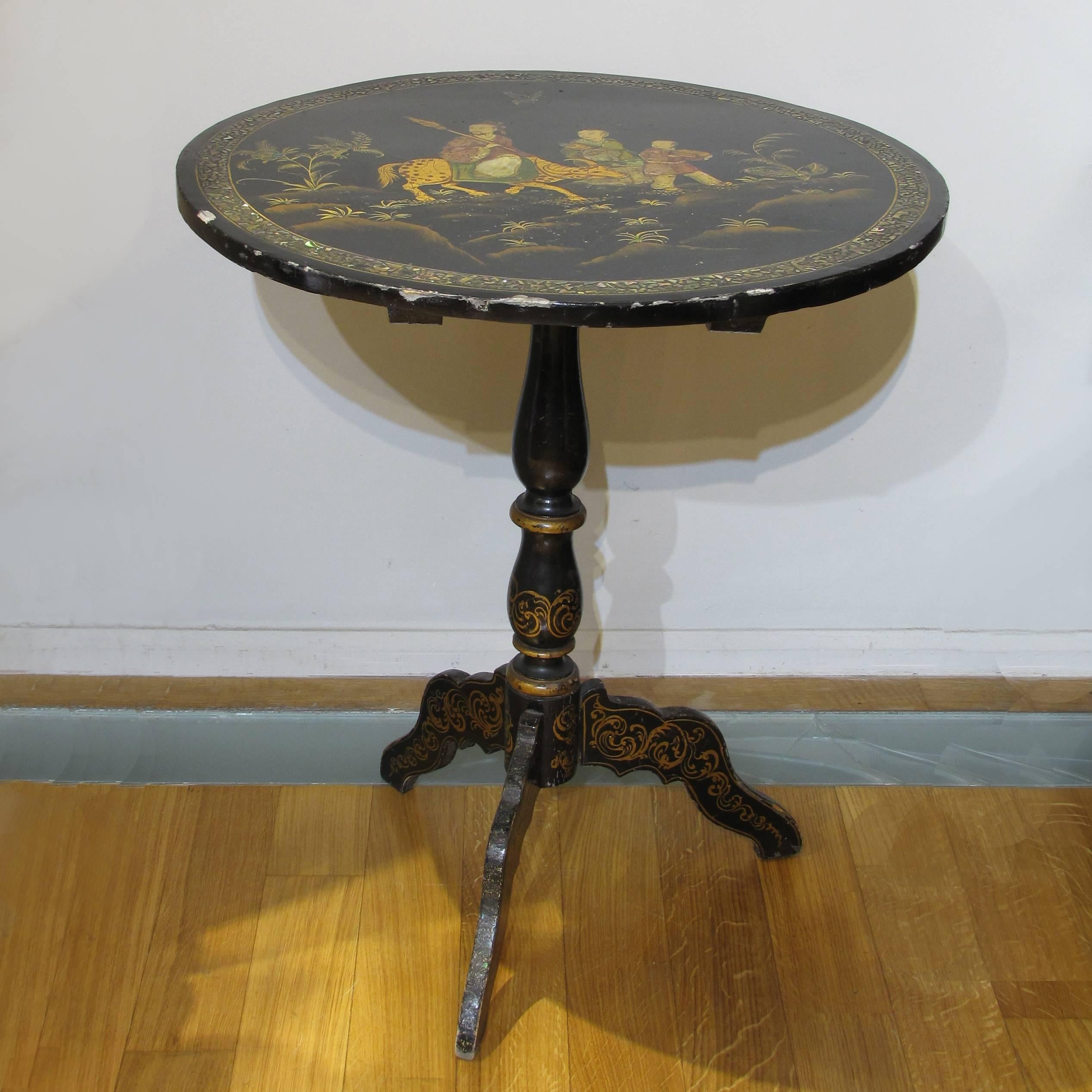 A particular Regency period lacquered Chinese tilt-top center table standing on a tripod base, circa 1820.
The tabletop features a hand painted polychrome oriental decoration depicting a scene of Chinese mythology and is decorated with mother of