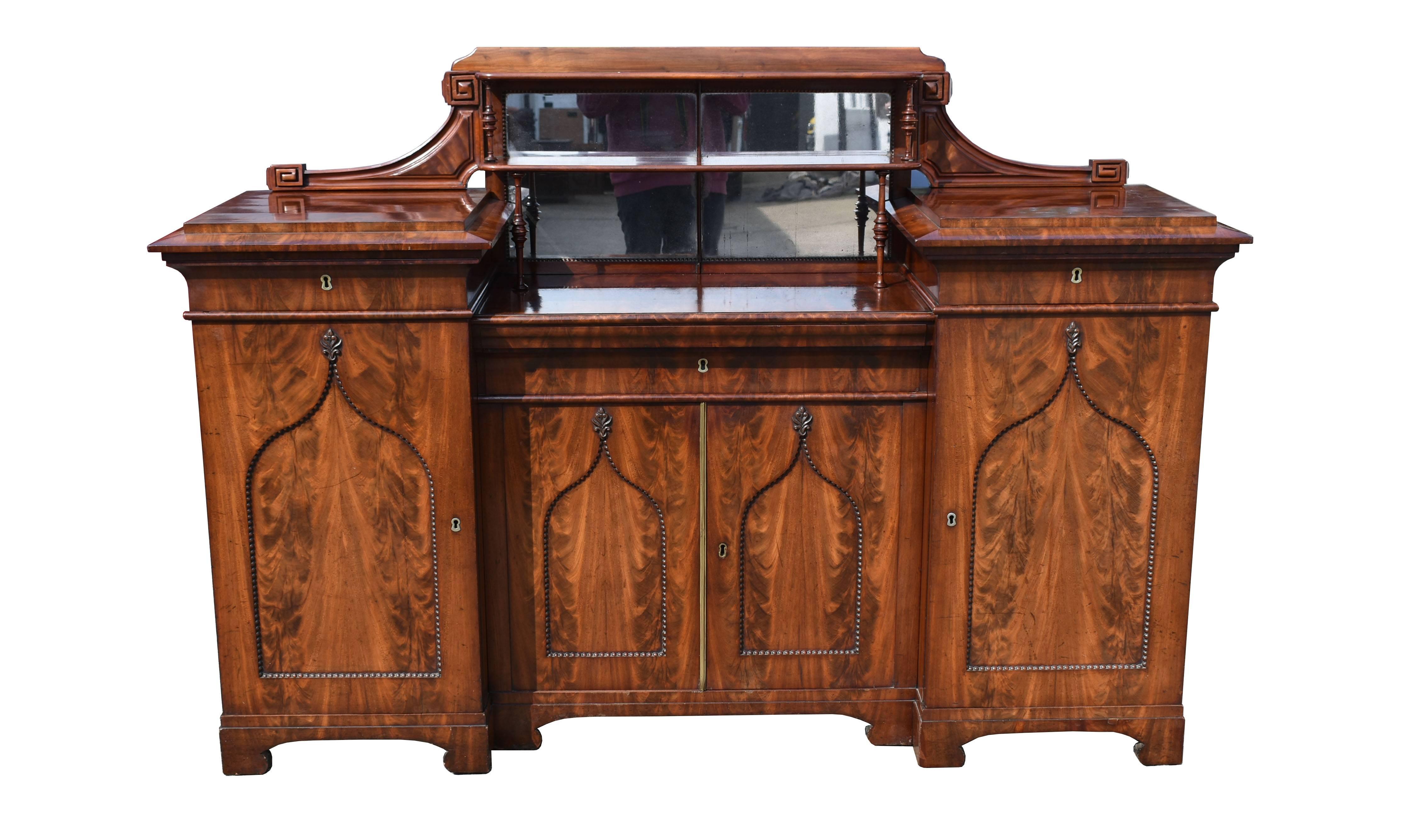 For sale is a fine quality Regency flame mahogany four-door sideboard. The top of the sideboard has an upstand, with two mirrors and four nicely turned supports, flanked by two brackets with a gallery to the top. On either side of the sideboard,