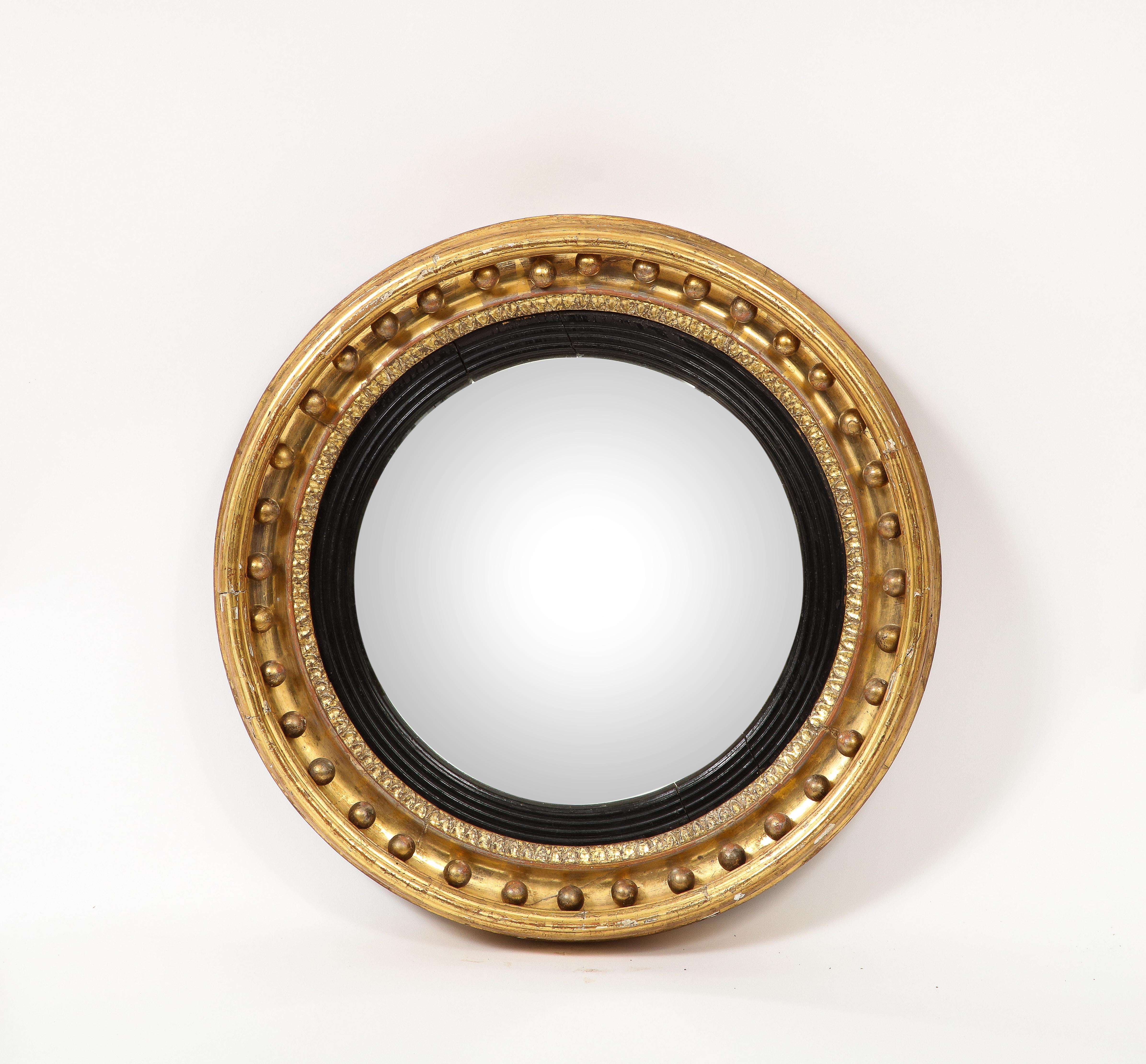 19th century Regency giltwood mirror with a convex plate and ebonized ring. 