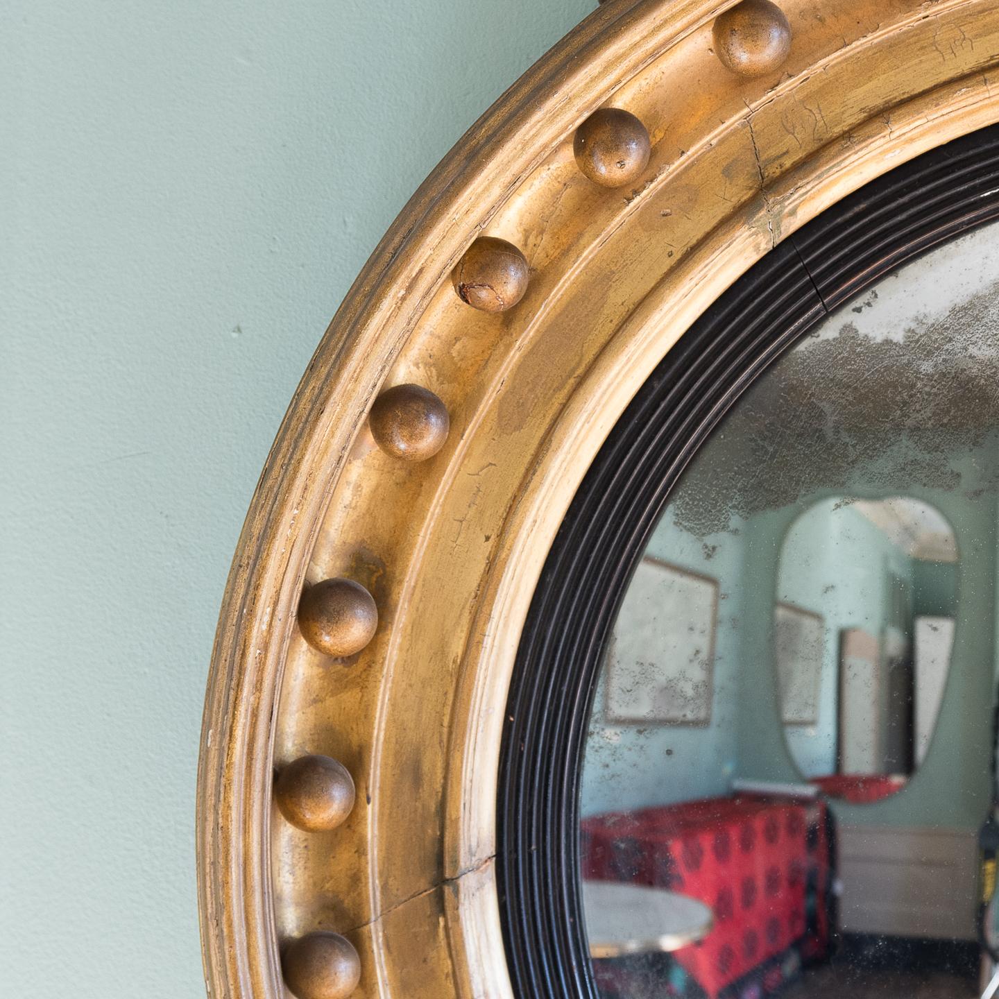 19th century giltwood Regency period convex mirror, circa 1820, with typical ball decoration to the frame and ebonized reeded slip surrounding original convex mirror plate.

The piece is in good original and untouched condition with some old