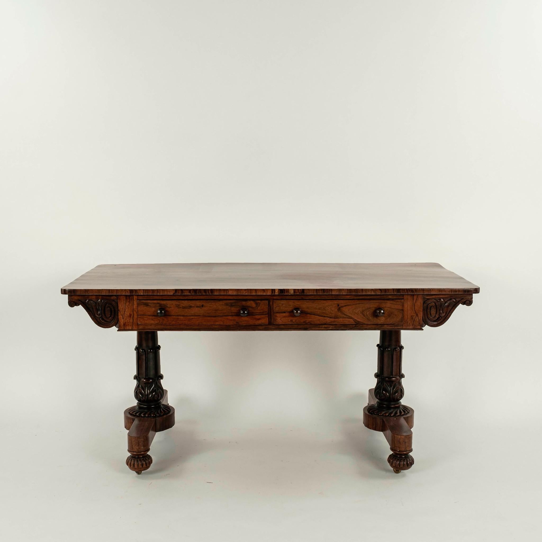 Early 19th century walnut two drawer library table supported by hand carved and turned trestle legs.
