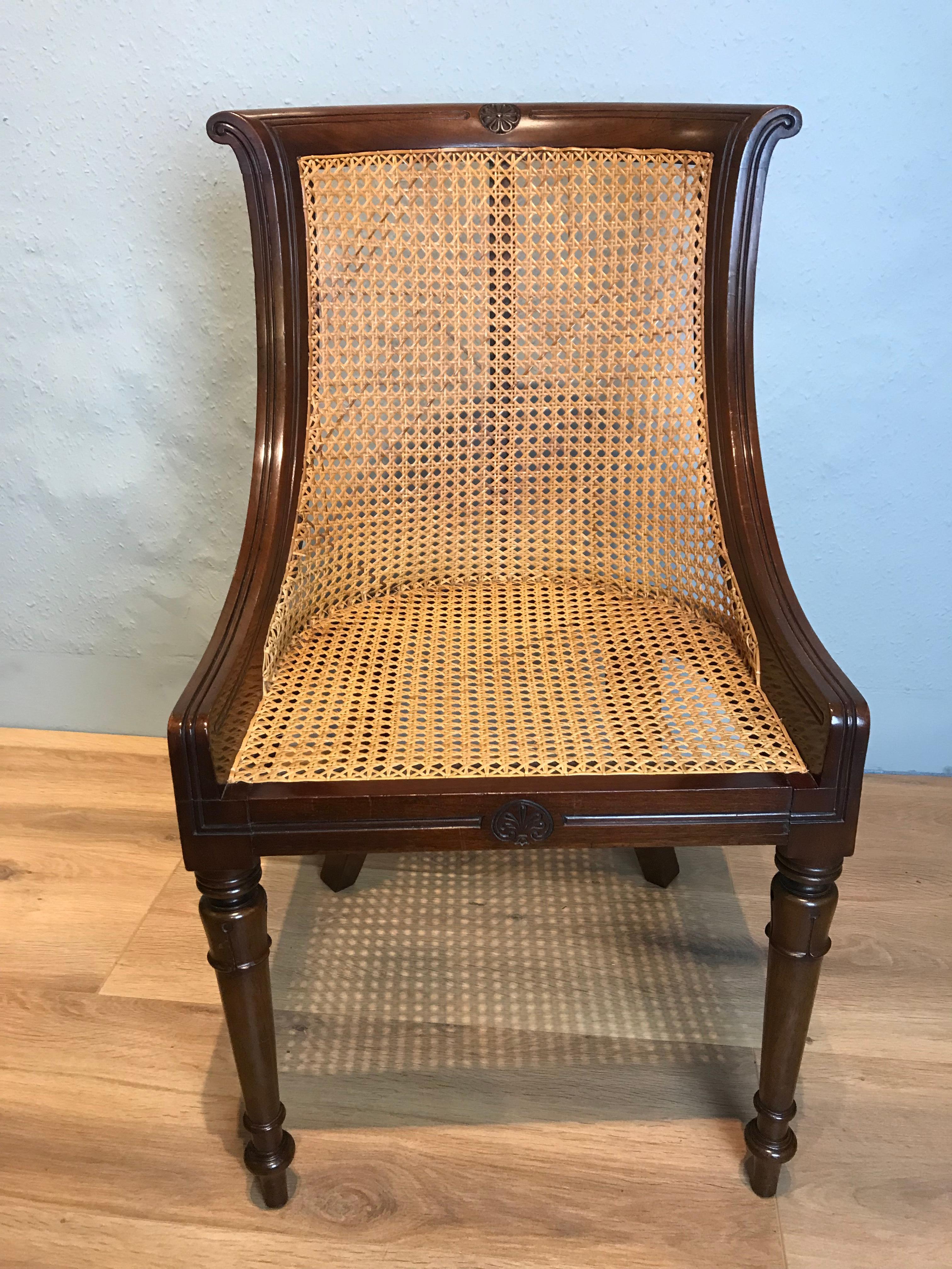 Attractive Regency caned Bergere chair, with original horse hair squab. The mahogany used has a rich colour and patina, the back is shaped and flows elegantly. The curved scrolled top rail has a flower decoration and reeded mouldings running down