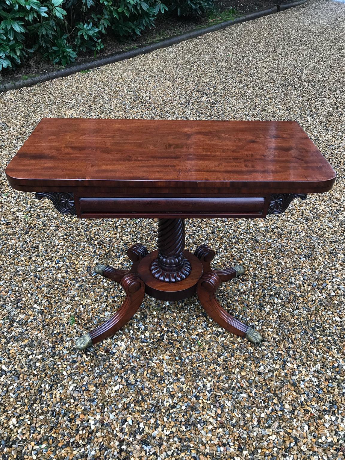 An original 19th century Regency mahogany card table with baize interior. The carved cylindrical central column which has four splayed feet on original brass claw castors. The top swivels open to become a card table,

circa