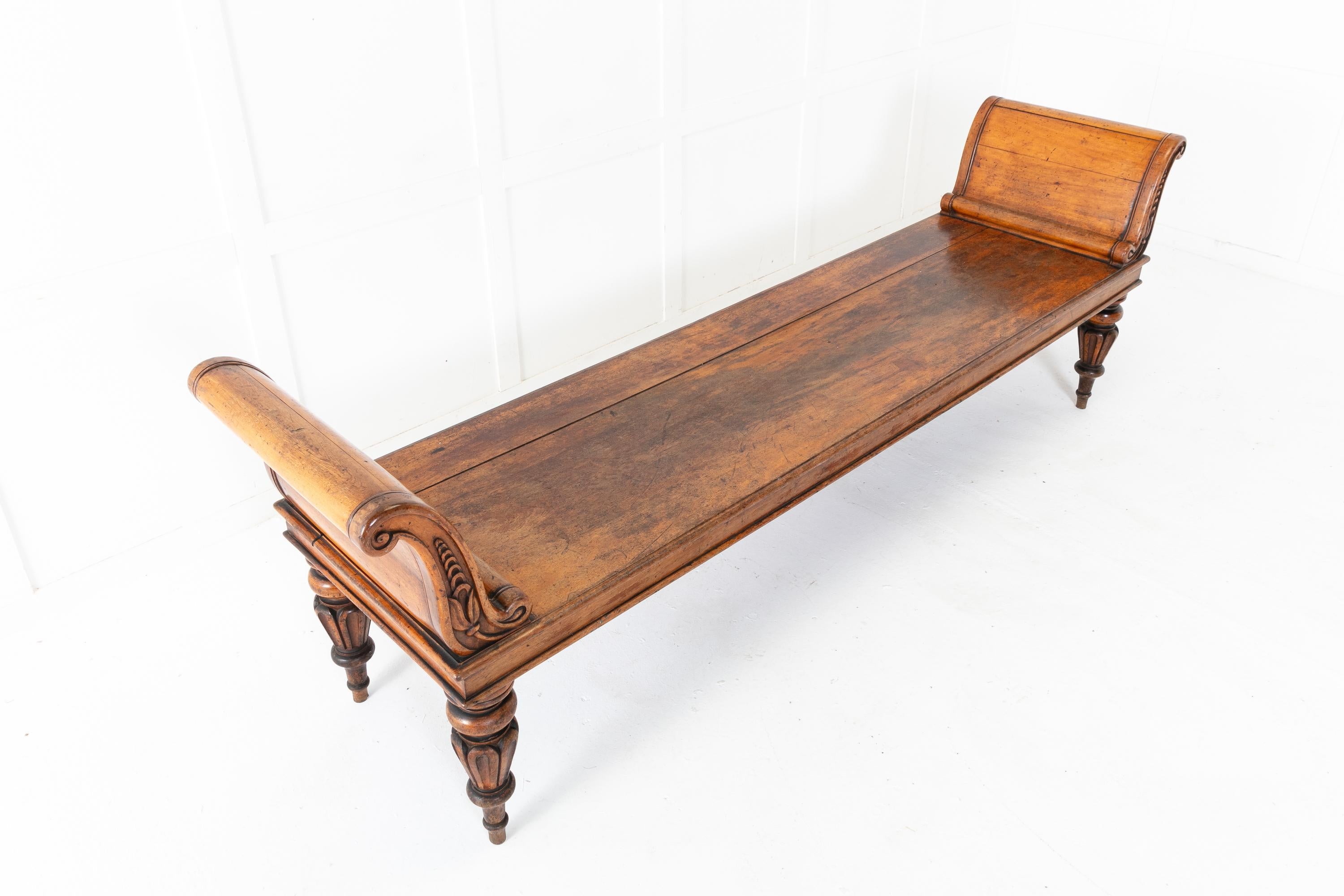 An exceptional, large, late Regency mahogany hall seat/hall bench of powerful scale. Having impressive 's' scroll ends with solid panels and carved mouldings with foliage. The large, rectangular seat has a moulded edge and a plain frieze below.