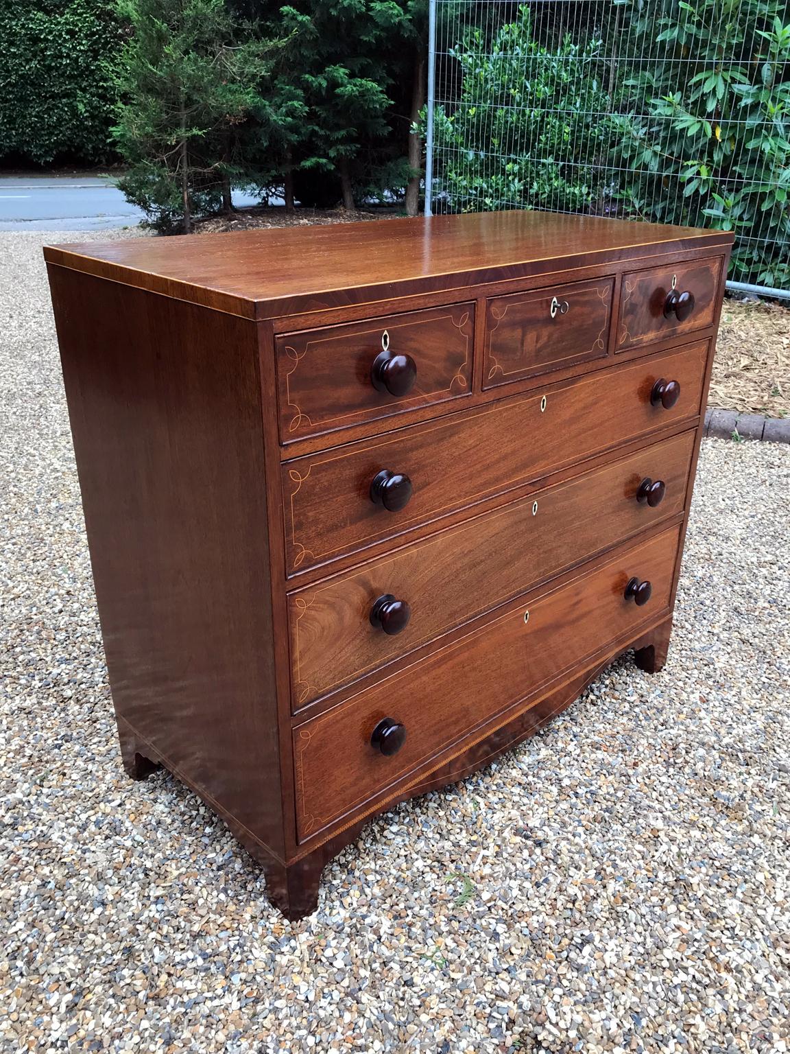 A very high quality, 19th century George IV – Regency mahogany inlaid chest of drawers with three short and three graduated long oak lined drawers with wooden turned bun handles and ivory escutcheons, on bracket feet,

circa