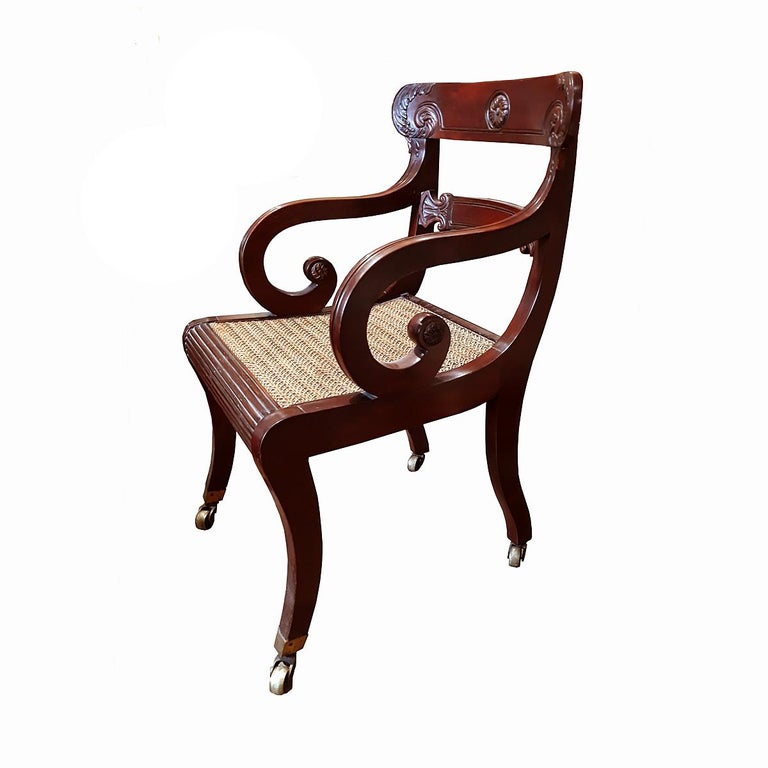 A very well preserved Regency period library chair. 
Cane seat, ornately carved back, bronze casters, circa 1820. 
Includes tapestry cushion.