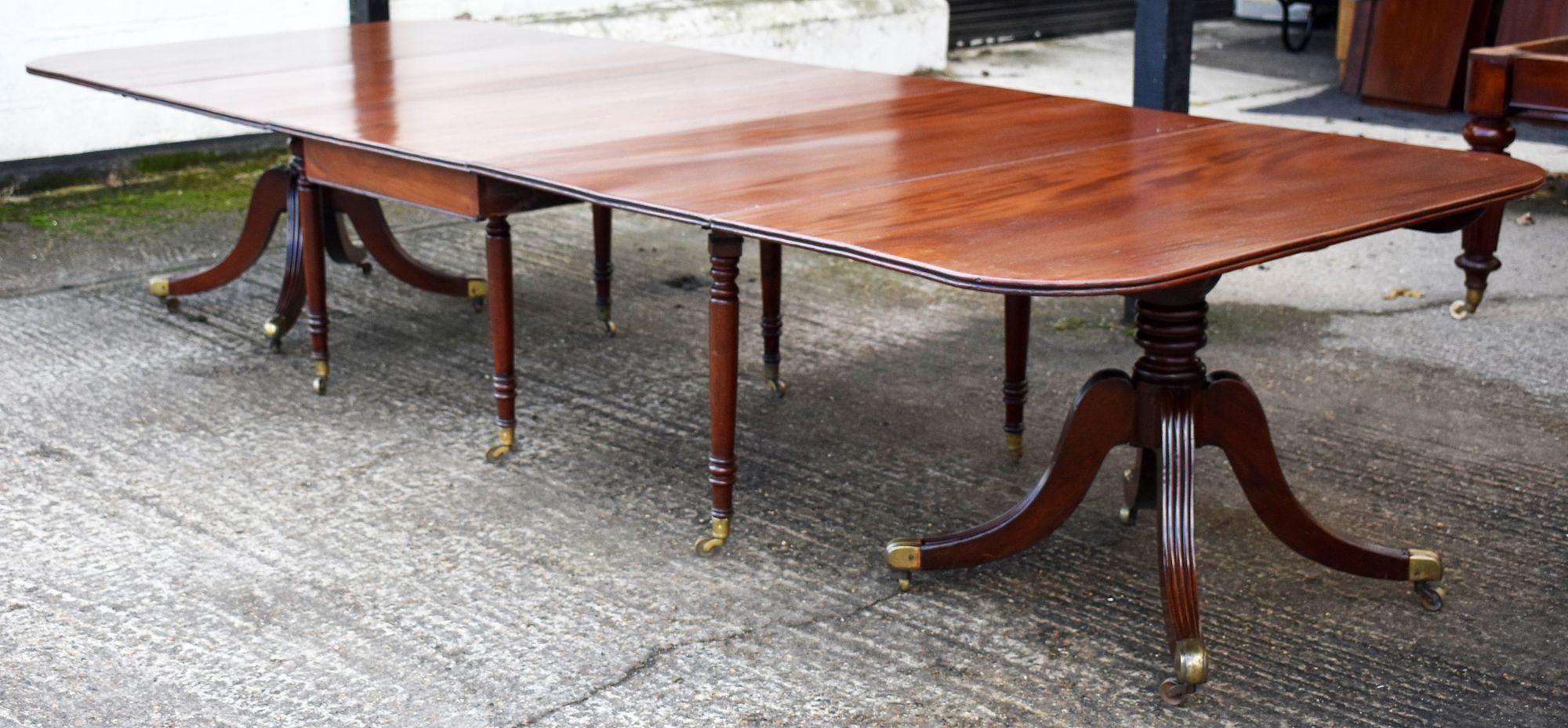 Nous vendons une table de salle à manger en acajou de style Regency de très bonne qualité. Chaque extrémité est soutenue par un piédestal tourné au-dessus de quatre jambes balayées, terminées par des roulettes en laiton, flanquant une section